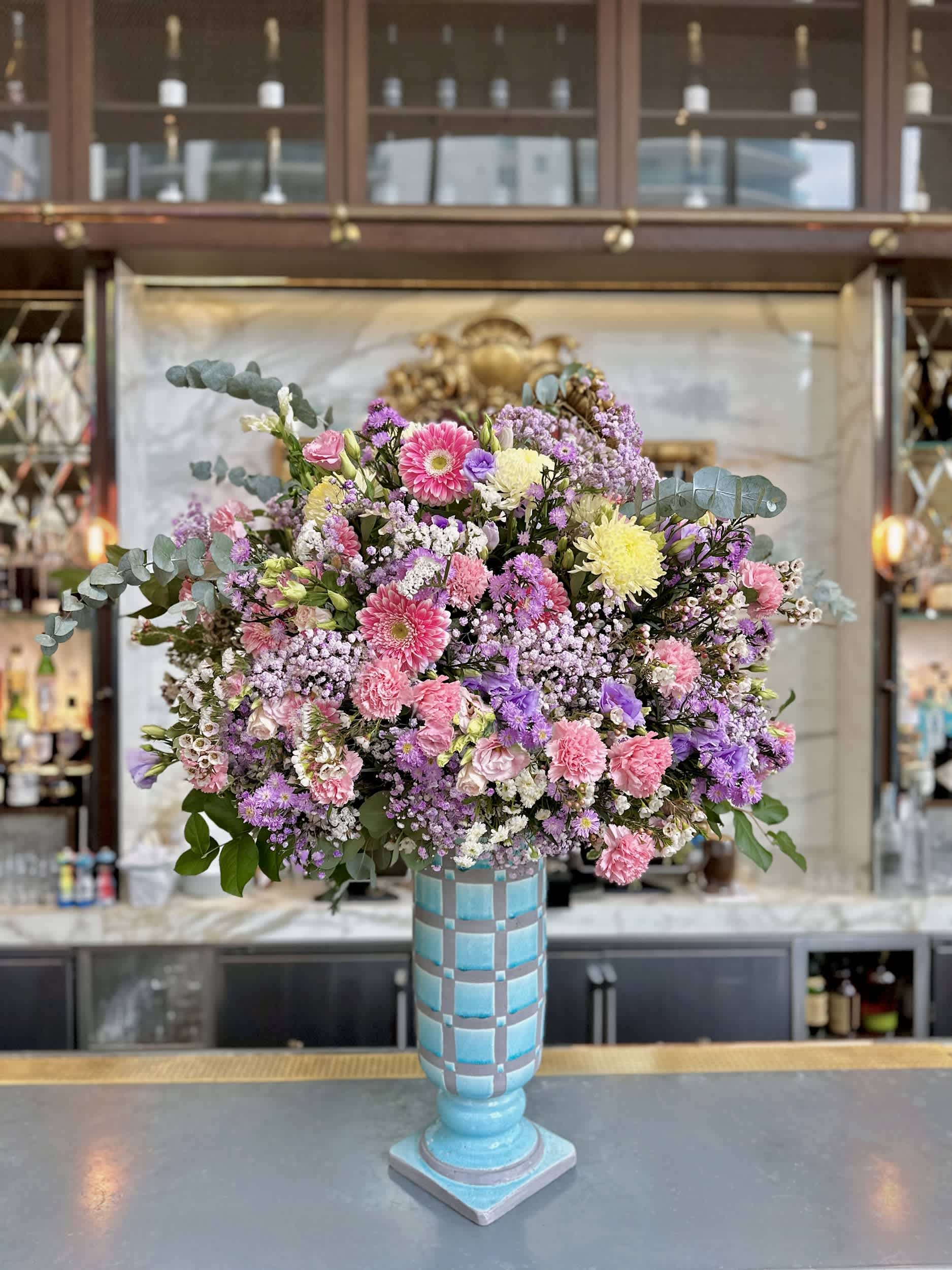 Grand Garden Delight Vase - The &quot;Grand Garden Delight Vase&quot; exudes elegance with a lush blend of chrysanthemums, gerbera daisies, and carnations. This stunning arrangement is highlighted with lisianthus and delicate baby's breath, all set in a tall, artistic vase. The symphony of pink, purple, and white blooms creates a captivating display perfect for any refined setting. Vase styles may vary slightly; please contact us for current options.  Arrangement Details: Main Flowers: Chrysanthemums, Gerbera Daisies, Carnations, Lisianthus, Baby's Breath Container: Tall artistic vase (styles may vary, please call for current options) Approximate Dimensions: 24&quot;D x 48&quot;H