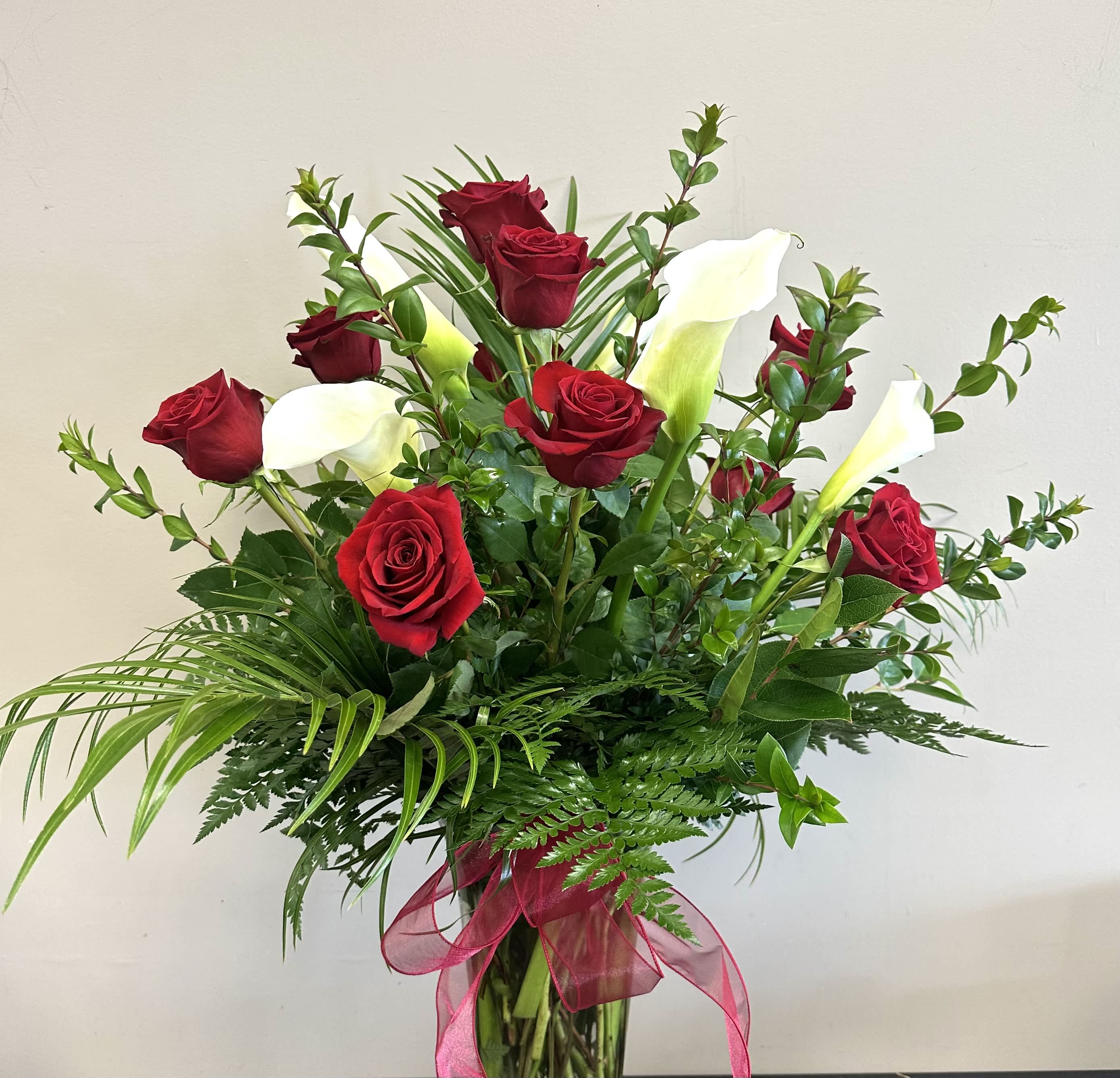 Lovely Lovely - A dozen rich, red roses and five stems of large white calla lilies.