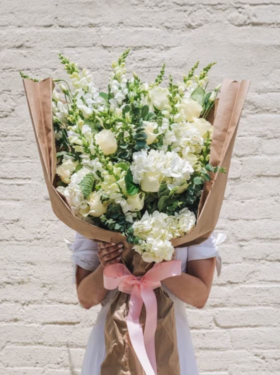 White wrapped Bouquet - An assortment of beautiful white flowers includes Roses, snap dragons, lilies, hydrangeas-stock, Mums, carations, alstrmerias and more 