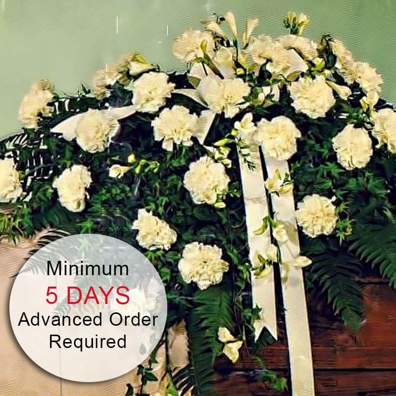 Divine Peace (Closed Casket, Large) - A larger version of our Divine Peace arrangement, this elegant and classic casket spray is highlighted with white carnations and is perfect to celebrate the life of an elegant and classy individual. Measuring approximately 46&quot; wide, this arrangement offers a beautiful and heartfelt tribute. Due to the intricate design work, a minimum of 5 days' advance notice is required to ensure that the flowers can be properly staged for quality results. The piece is created as a one-sided arrangement for maximum visual value.  Key Features:  Stunning Dimensions: Measures approximately 46&quot; wide, creating an impressive and elegant display.  High-Quality Arrangement: Expertly crafted with fresh white carnations to ensure lasting beauty and impact.  One-Sided Design: Created as a one-sided piece for maximum visual value and elegance. Elegant Presentation: Perfect for memorials, celebrations of life, or any event where a stylish and beautiful tribute is desired.  Meaningful Tribute: Designed to honor and celebrate the life of a loved one with grace and elegance.  Advanced Notice Required: A minimum of 5 days' notice is needed to ensure the flowers can be staged for the best quality results.  Celebrate and honor the memory of a loved one with our Larger Divine Peace Casket Spray, a beautiful and meaningful tribute that reflects love and remembrance.