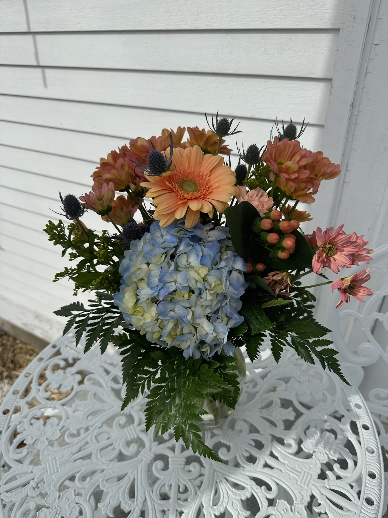 Deal of the day Beachwalk Bouquet Deal of the day Beachwalk Bouquet - Blue hydrangea, peach gerbera daisys, hypericum berries and daisys arranged in vase