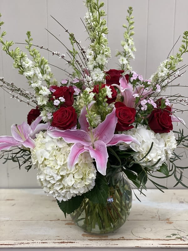 Alhambra Alhambra - A true classic beauty with a modern twist, including roses, lilies, hydrangea and larkspur in hues of reds, pinks and whites. What at way to make a dramatic impression.