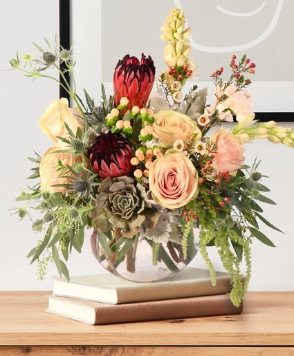 Mystic Meadow Mystic Meadow - Add a touch of decadence to your home with this stunning bouquet! The pink mink protea stands out gorgeously against the creamy tones of the roses, carnations, and more, creating a moment to remember. Send Mystic Meadow to someone you love or treat yourself!