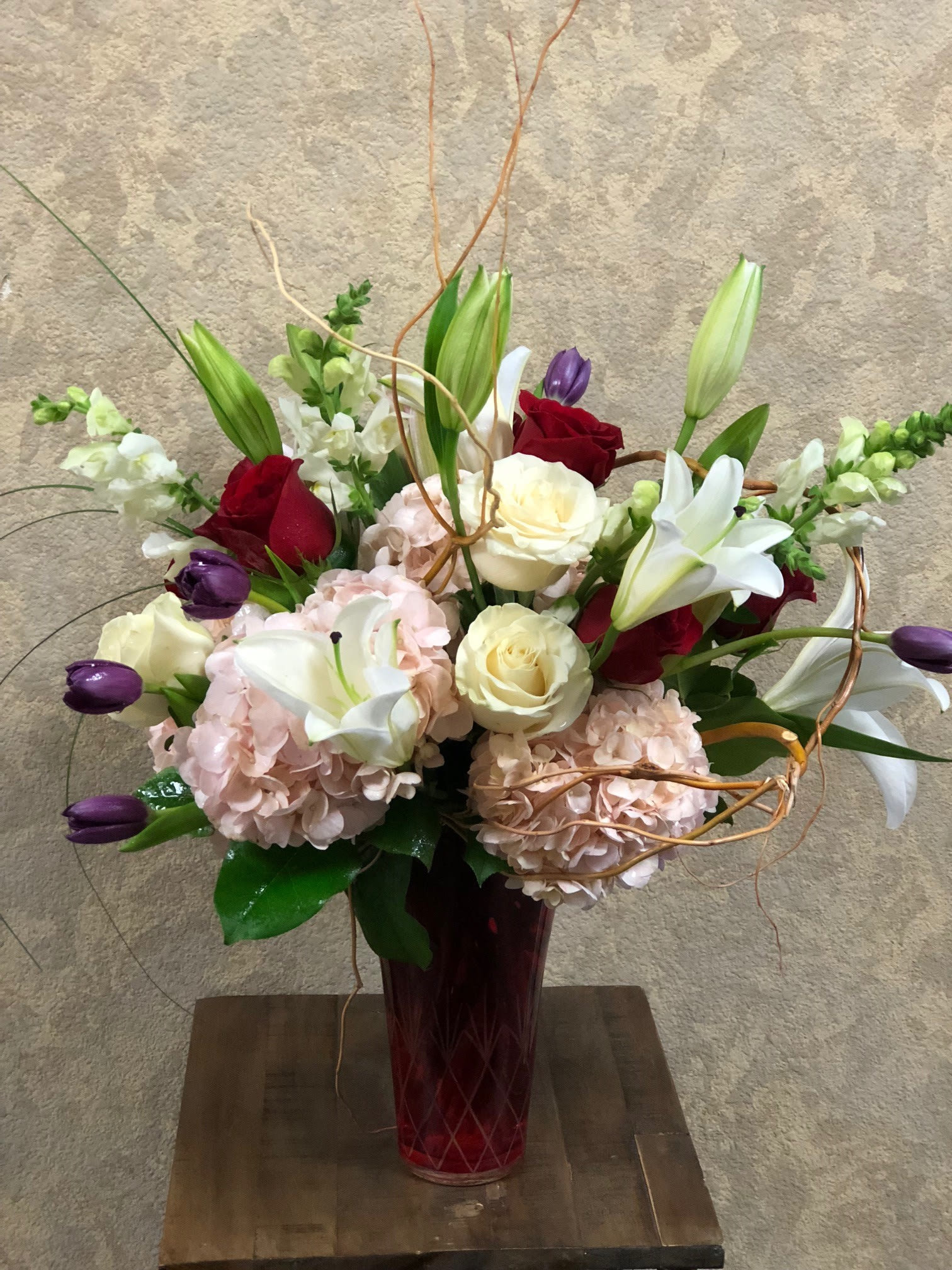 Elegance and Beauty Elegance and Beauty - Type of Flowers: Purple Tulips, Red and White Roses, White Asiatic Lillies, Pink Hydrangeas, White Snapdragons and branches in a red vase. Availability: All year round Substitute Available: Yes Photo shown: Regular