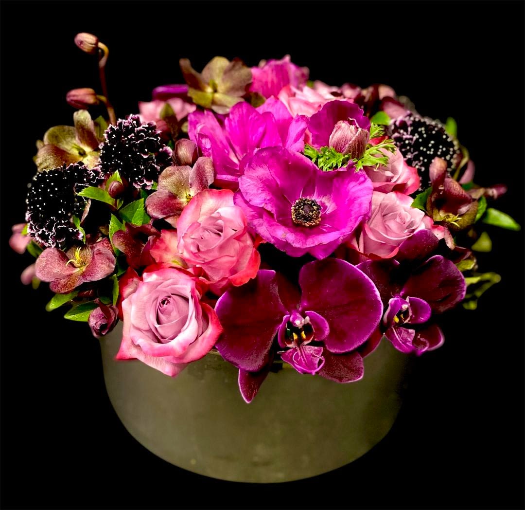 Tell me you love me - This gorgeous design includes a variety of luscious premium blooms in rich shades of Plum, Magenta, and Lavender.  This design includes Roses, Phalaenopsis Orchids, Scabiosa, Hellebores, and Anemones. This design measures approx. 13&quot;W x 9&quot;H. This design can be made in various color schemes. Please contact the office directly for options.