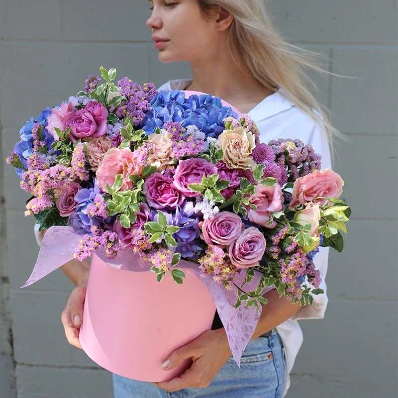 Glow - This beautiful arrangement combines pink, purple, and blue flowers in an round box. Perfect for any occasion or to brighten up your space, it includes fresh roses, garden roses, hydrangeas, and other seasonal blooms for a charming, colorful touch.