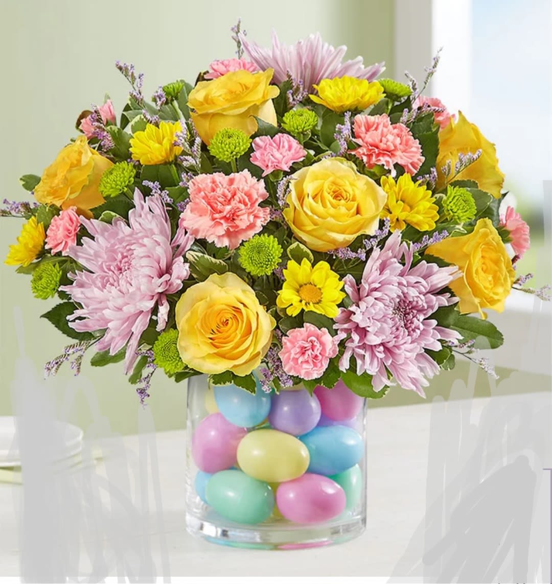 RAINBOW - A beautiful arrangement featuring a composition of daisies and carnations in the vibrant colors that characterize this season, and a base decorated with Easter eggs, perfect for any event or to brighten your loved one's day.