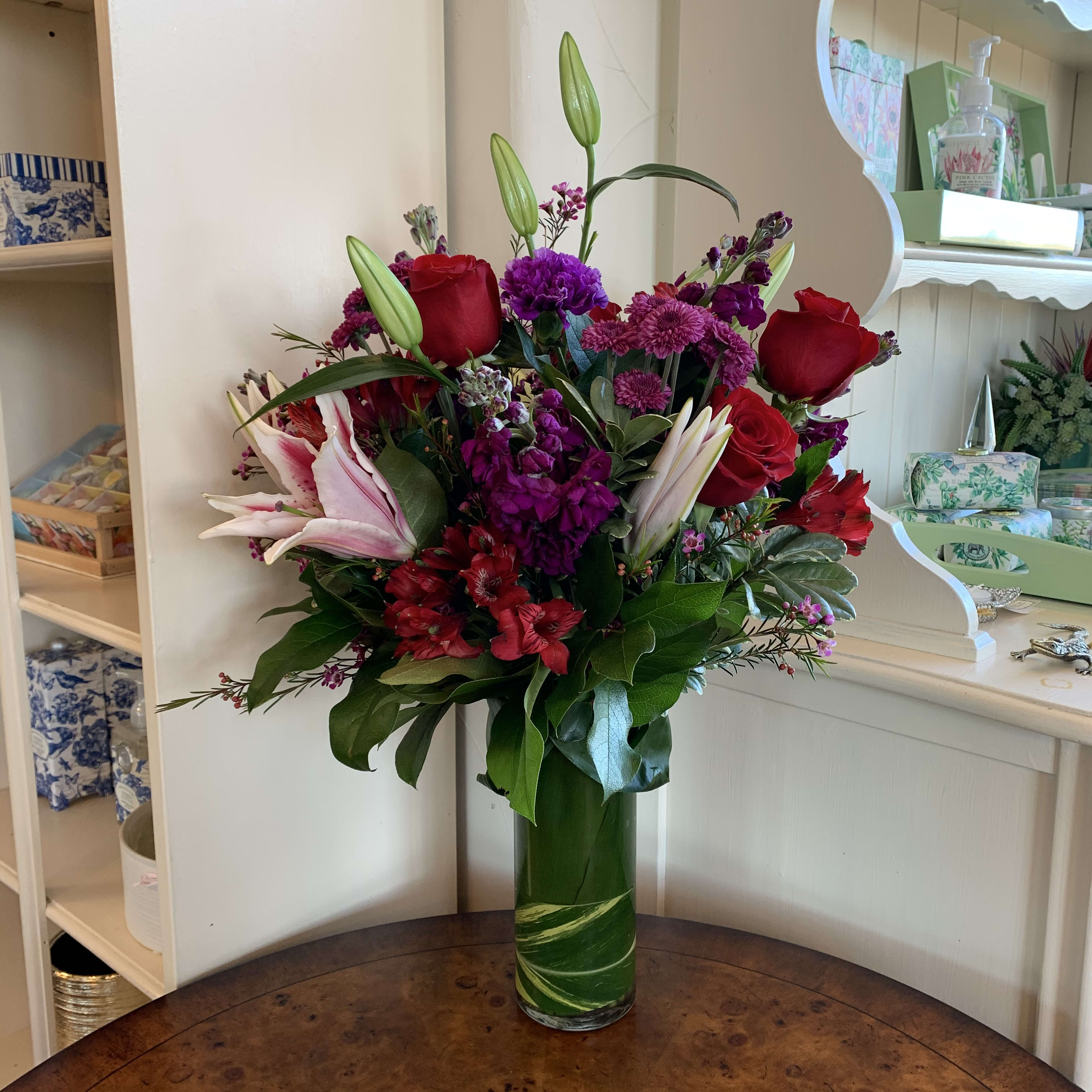 Stunning Beauty Bouquet - The Stunning Beauty Bouquet blooms with rich bold blooms making this a fresh flower bouquet that simply n0ever goes out of style! Fragrant Stargazer Lilies take center stage of this arrangement as they stretch their long star-shaped blooms across a bed of red roses purple double lisianthus lavender carnations red Peruvian Lilies purple matsumoto asters and lush greens. Presented in a leaf lined 9&quot; cylinder glass vase this gorgeous bouquet is created just for you to help you celebrate an anniversary a birthday or to simply say thank you. REGULAR bouquet is approx. 17&quot;H x 14&quot;W. DELUXE bouquet is approx. 19&quot;H x 16&quot;W. PREMIUM bouquet is approx. 21&quot;H x 19&quot;W.