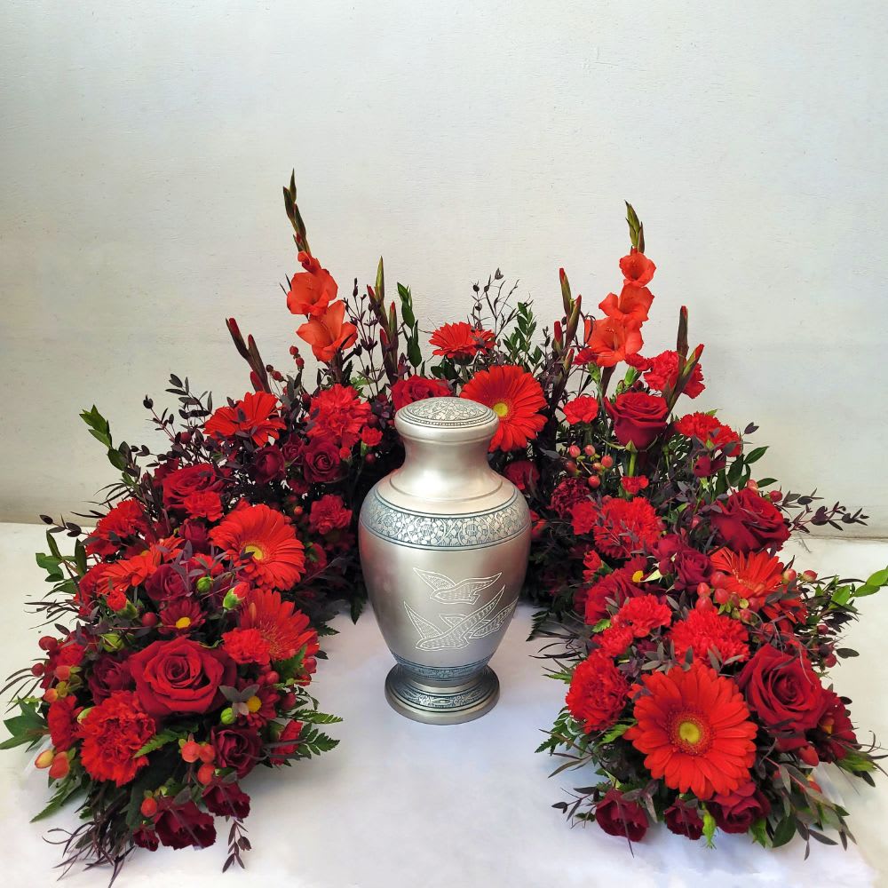 Crimson Embrace Urn Surround Crimson Embrace Urn Surround - Crimson Embrace Urn Surround made with beautiful red blooms and lush greens Approximate size 22" Wide x 16" Tall In special instructions, indicate size and shape of urn