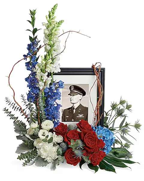 Always With Us Photo Tribute Bouquet - Honor the memory of an always-beloved with this beautiful display bouquet. Designed to surround a favorite photo, its patriotic mix of blue hydrangea with red and white roses is a respectful tribute. This bouquet features blue hydrangea, red roses, red spray roses, white spray roses, white carnations, blue delphinium, white snapdragons, blue eryngium, dusty miller, curly willow, spiral eucalyptus, parvifolia eucalyptus, aralia leaf and lemon leaf. Arrangement does not include picture frame.  