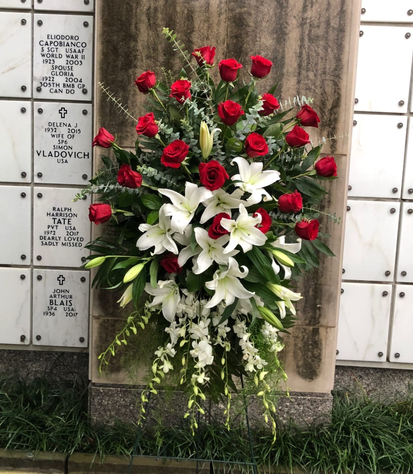 Lily and Rose Tribute Spray - Pure white lilies and dendrobium orchids mingle with red roses, white asiatic lilies and more in this magnificent and impressive standing spray of the finest blooms. A fitting tribute for a funeral, wake or memorial service.  A standing spray of lush flowers such as red roses, white dendrobium orchids and asiatic lilies - accented with greenery - is delivered on an easel.  Approximately 31&quot; W x 50&quot; H  Orientation: One-Sided  As Shown : T226-1A