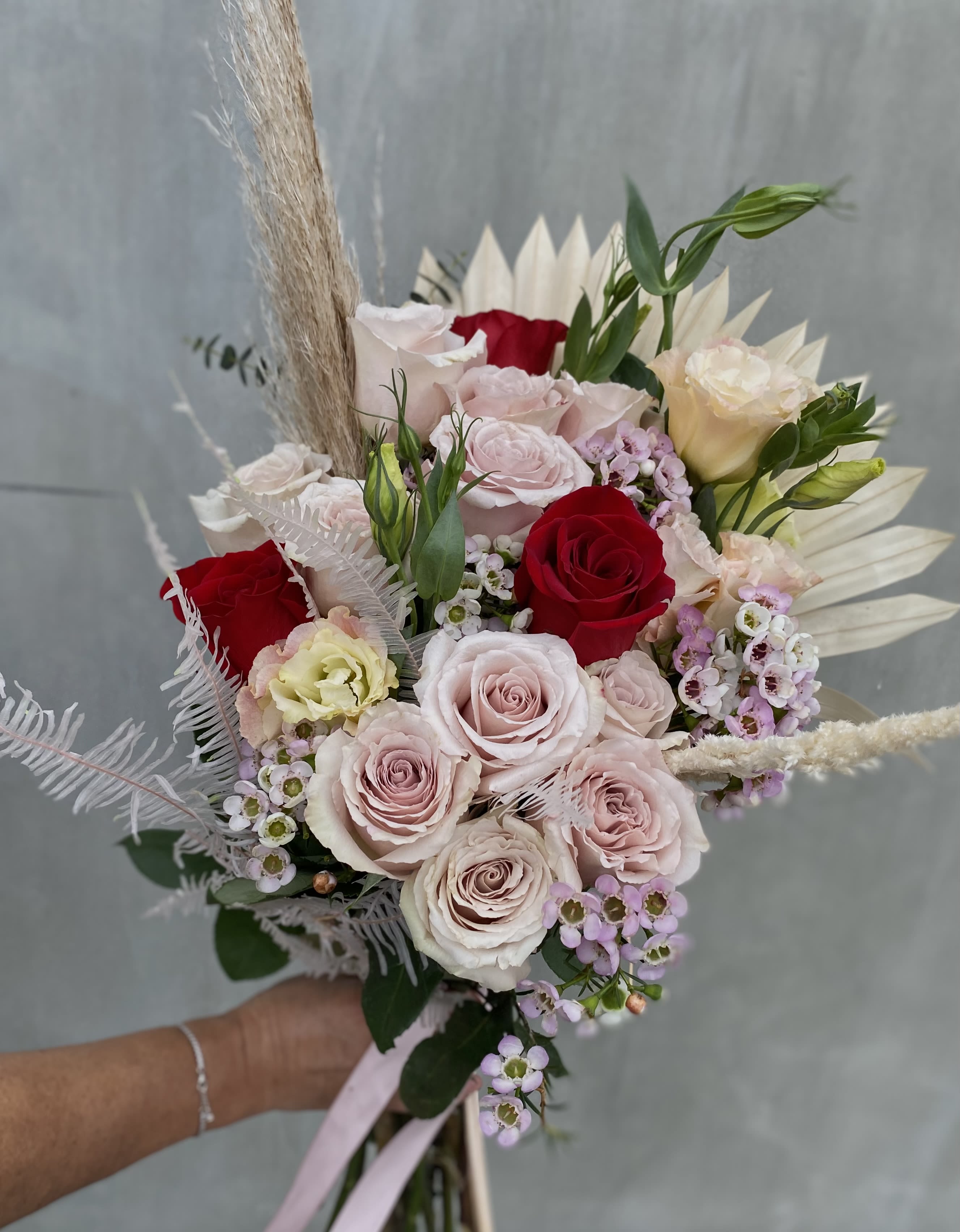 Boho Chic - This romantic bouquet features blush and red roses, wax flowers, and pampas grass, blending elegance with a modern touch.