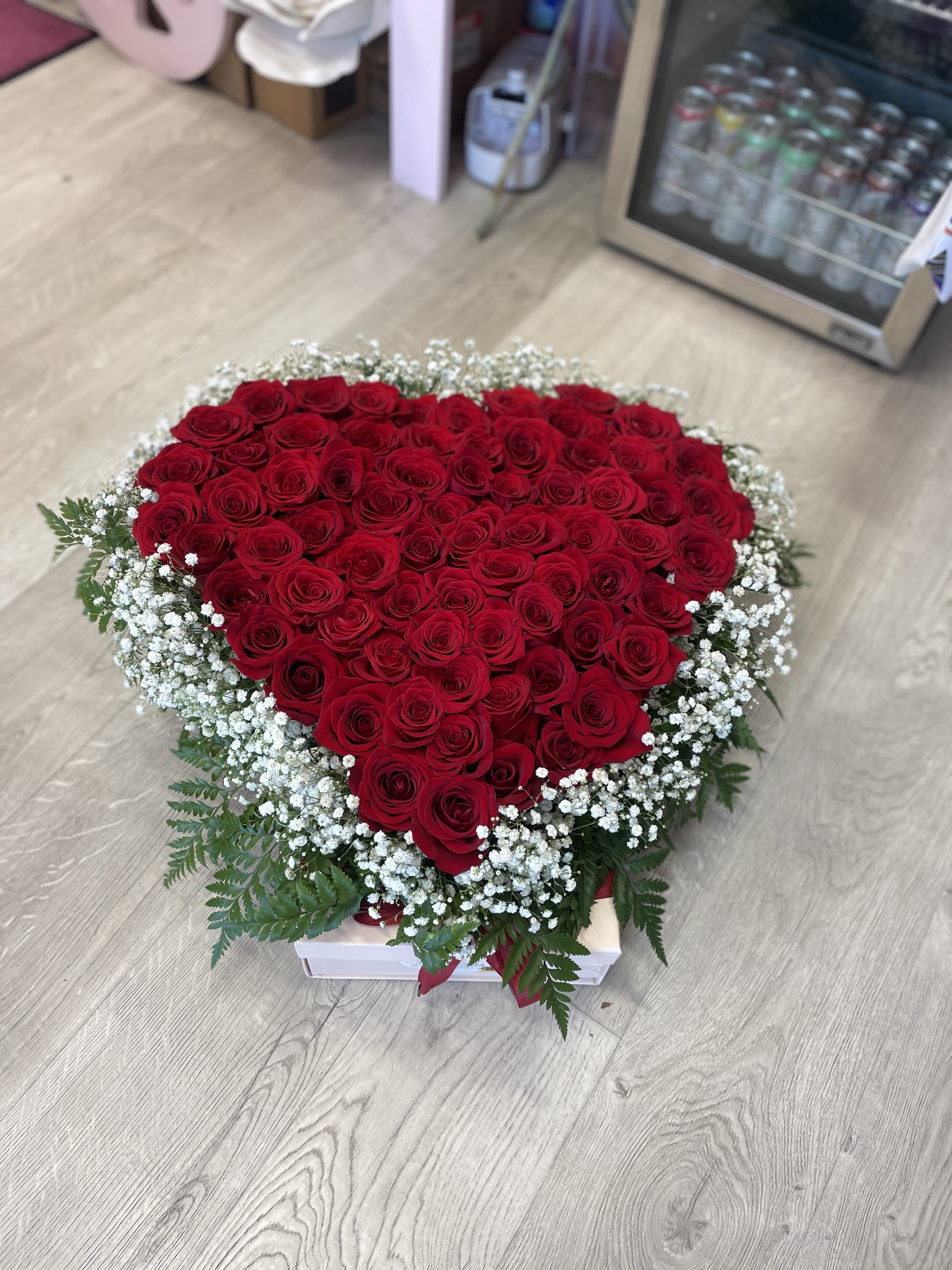 You Have a Big Heart - This luxurious red heart is a breathtaking masterpiece, featuring over five dozen deluxe roses that radiate love and passion. Each rose is carefully selected for its rich, velvety petals, creating a striking display that captures the essence of romance. Complementing the roses are delicate sprigs of baby’s breath, adding a touch of whimsy and softness, while lush fern greenery provides a beautiful backdrop, enhancing the overall elegance of this stunning arrangement.  This heart-shaped bouquet is a versatile expression of affection, making it the perfect term of endearment for Valentine’s Day, weddings, or even to honor the memory of a loved one during funerals. Its vibrant color and exquisite composition convey deep emotions, whether celebrating a joyous occasion or offering comfort during a time of loss.  Presented with care and artistry, this luxurious heart is more than just a floral arrangement; it’s a heartfelt symbol of connection, love, and remembrance. Let it speak for you, conveying your sentiments in the most beautiful way possible.