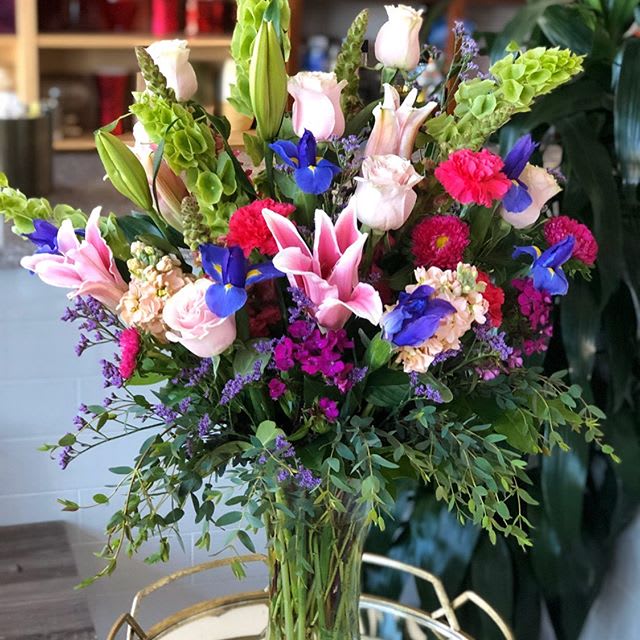 Color me with Love  - Bouquet includes as shown Green Bells, Roses, Blue Iris, Stargazers, Carnation, Matsumoto and Fillers in a tall beautiful Ginger vase. Please note this is a one sided arrangement! 