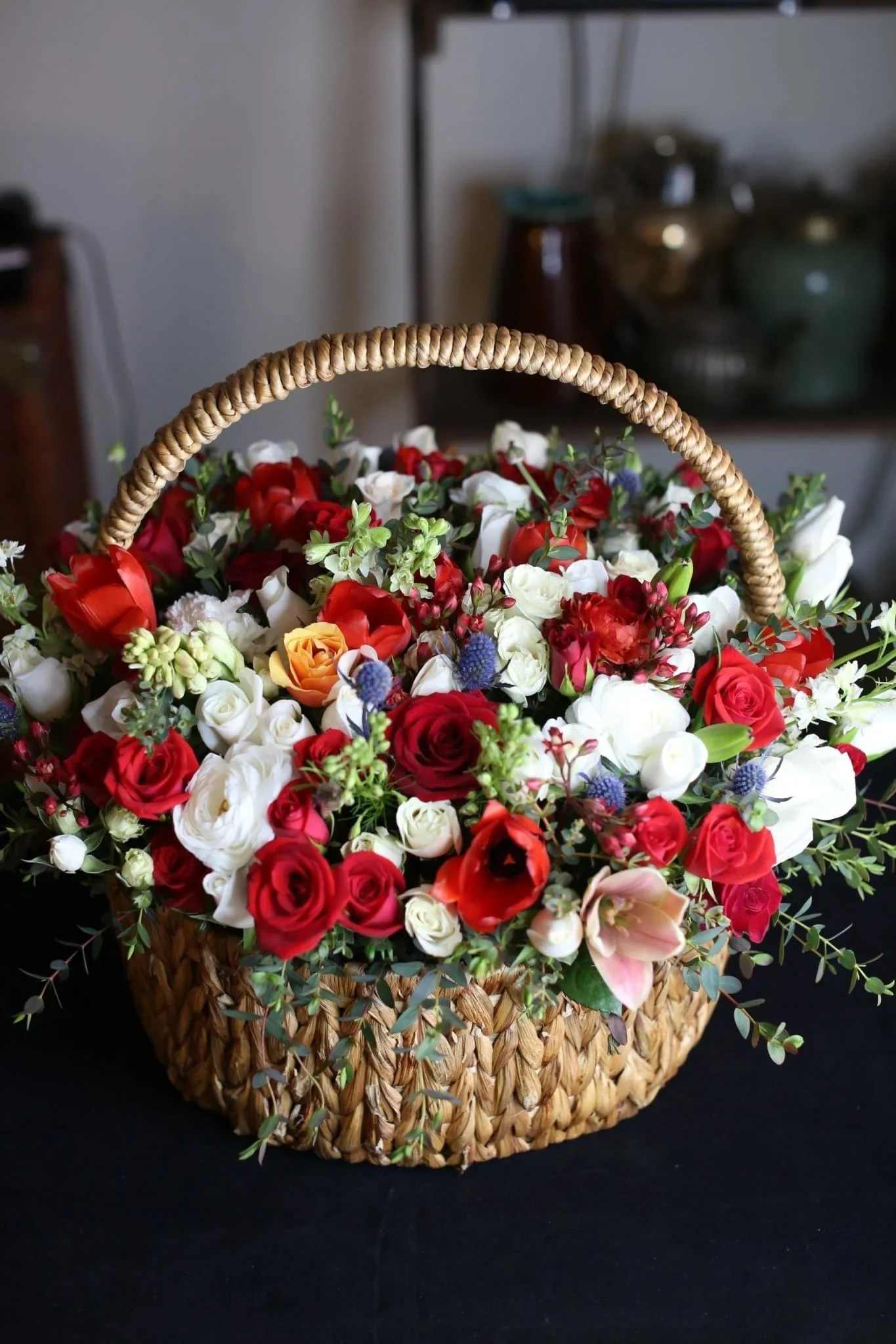 Flora - The basket of roses, ranunculus, delphinium, thistle and tulips flowers with Baby Blue Eucalyptus leaves. Such flower composition will fit well for anniversary, Valentine's Day, birthday, sympathy, new baby, thank you and etc.