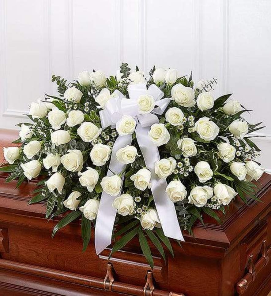 Casket Cover Memory - The precious moments spent with loved ones are the moments we want to hold onto forever. Capture this sentiment with a timeless display of all white. Our half casket cover, crafted with care and artistry by our expert florists with over 50 snow white roses, white monte casino, and accented with a white satin ribbon, is an unforgettable way to commemorate a lifetime of shared loving experiences.  