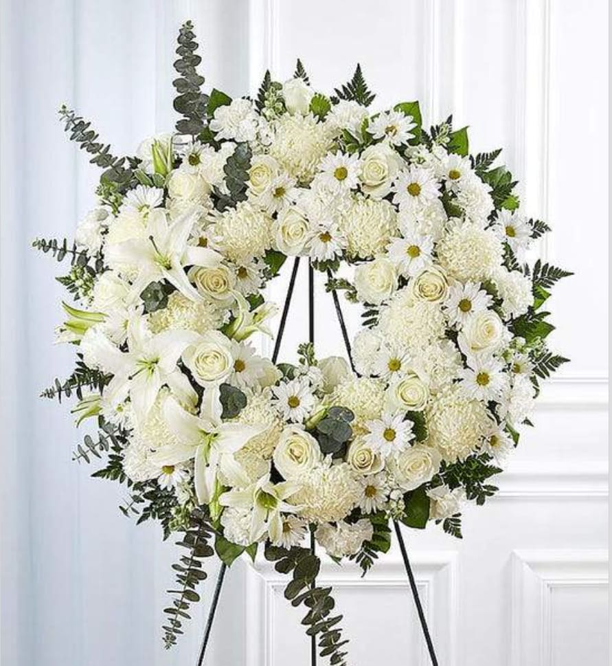 Circle spray White - Their pure heart and peaceful spirit will live on in a gesture symbolizing the circle of eternal life. Our standing wreath of soothing white blooms and fresh greenery, expertly crafted by our local florists for a lush, full presentation, is a grand expression of your condolences, offering hope and serenity during a difficult time.  Arrangement measures approximately 42&quot;H x 28&quot;L