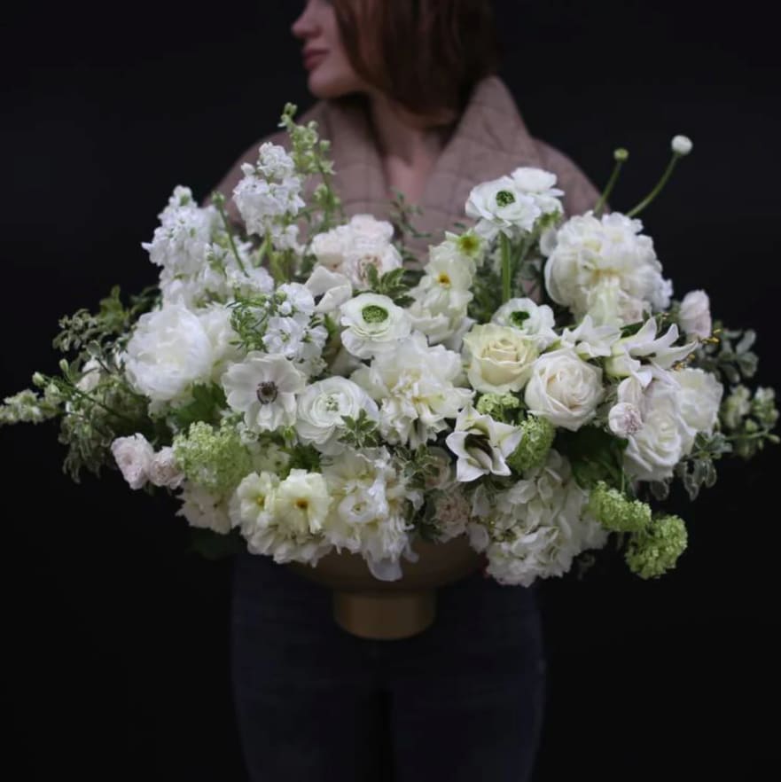 Centerpiece Pure Petals - A refined white floral centerpiece arranged in a golden vessel. Featuring anemones, tulips, ranunculus, roses, and hydrangeas, this design brings a soft, elegant touch to any event or home setting.