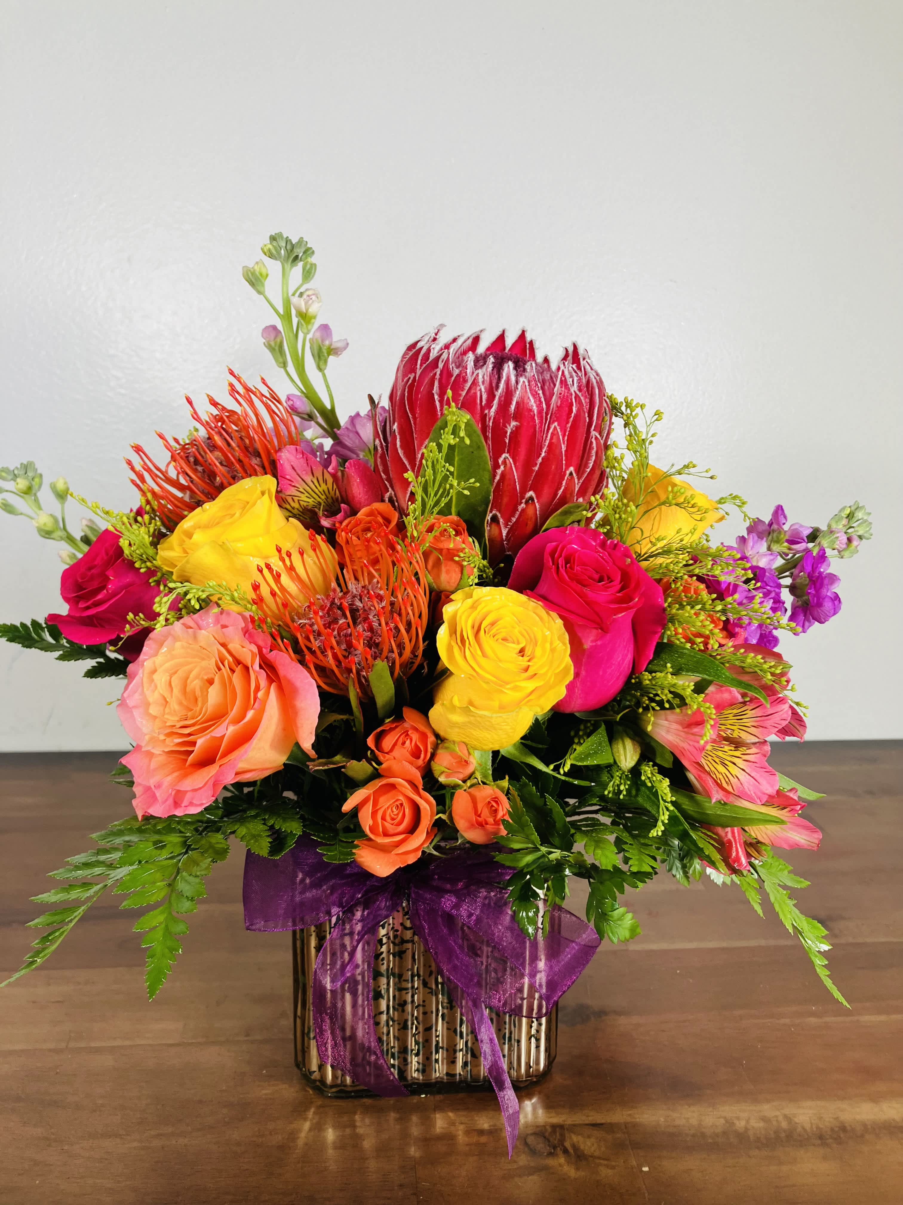 Sunny Delight Sunny Delight - Sunny Delight: a bright design made with warm colors to embolden your heart, enrichen your home and enhance your day. Main colors: pink, white, orange, yellow. Typically includes: Pink Ice Protea, Pincushion Protea, Orange Roses, Yellow Roses, Pink Roses, Orange Spray Roses. Subject to substitution.