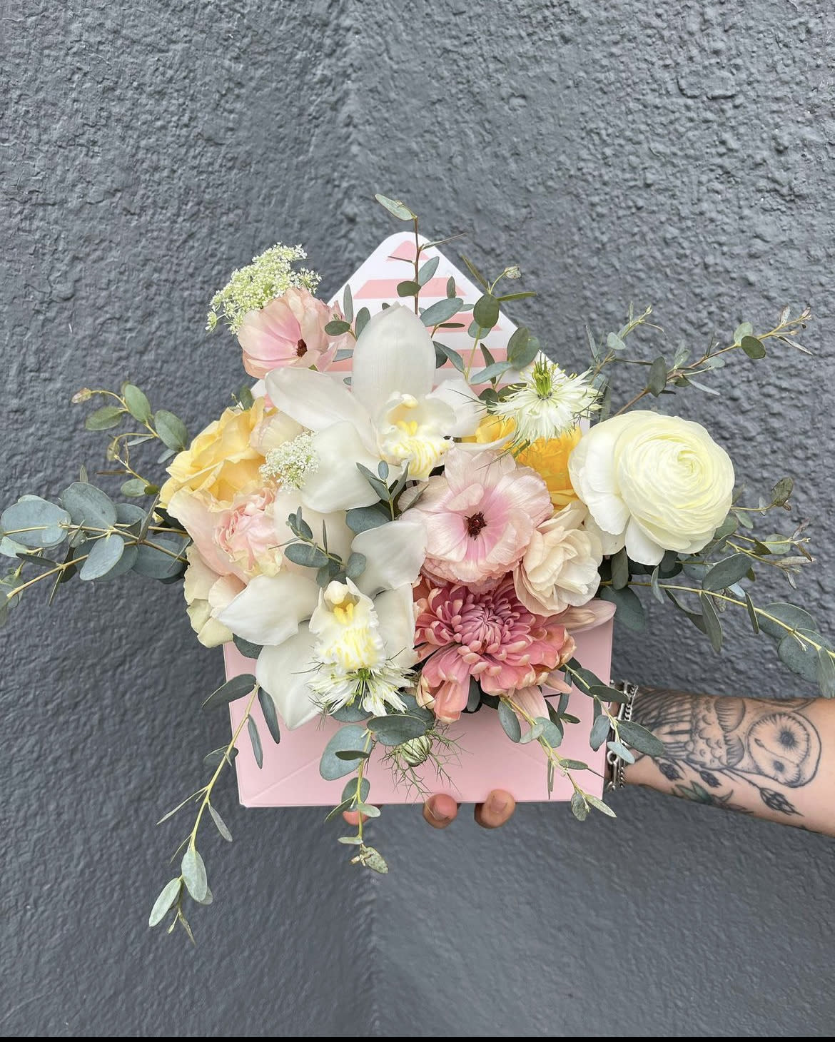 Spring Delivery - A charming spring arrangement in a soft pink envelope box. Floral varieties and colors may vary but the overall vibe will remain the same and in light spring colors.