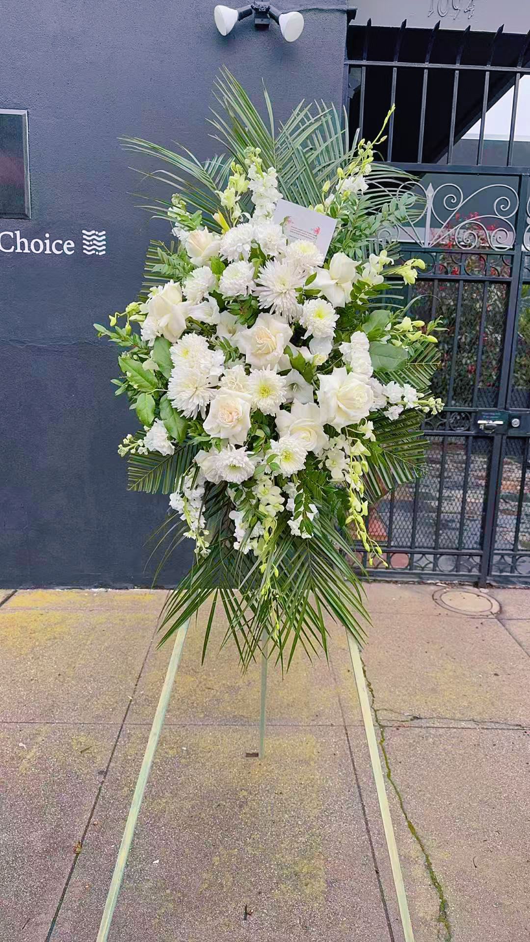 Sympathy Flower Stand Sympathy Flower Stand - An all white tribute, this funeral spray is pure and tranquil. Featuring a variety of white flowers and green palms this elegant funeral spray brings a feeling of peace to it's surroundings