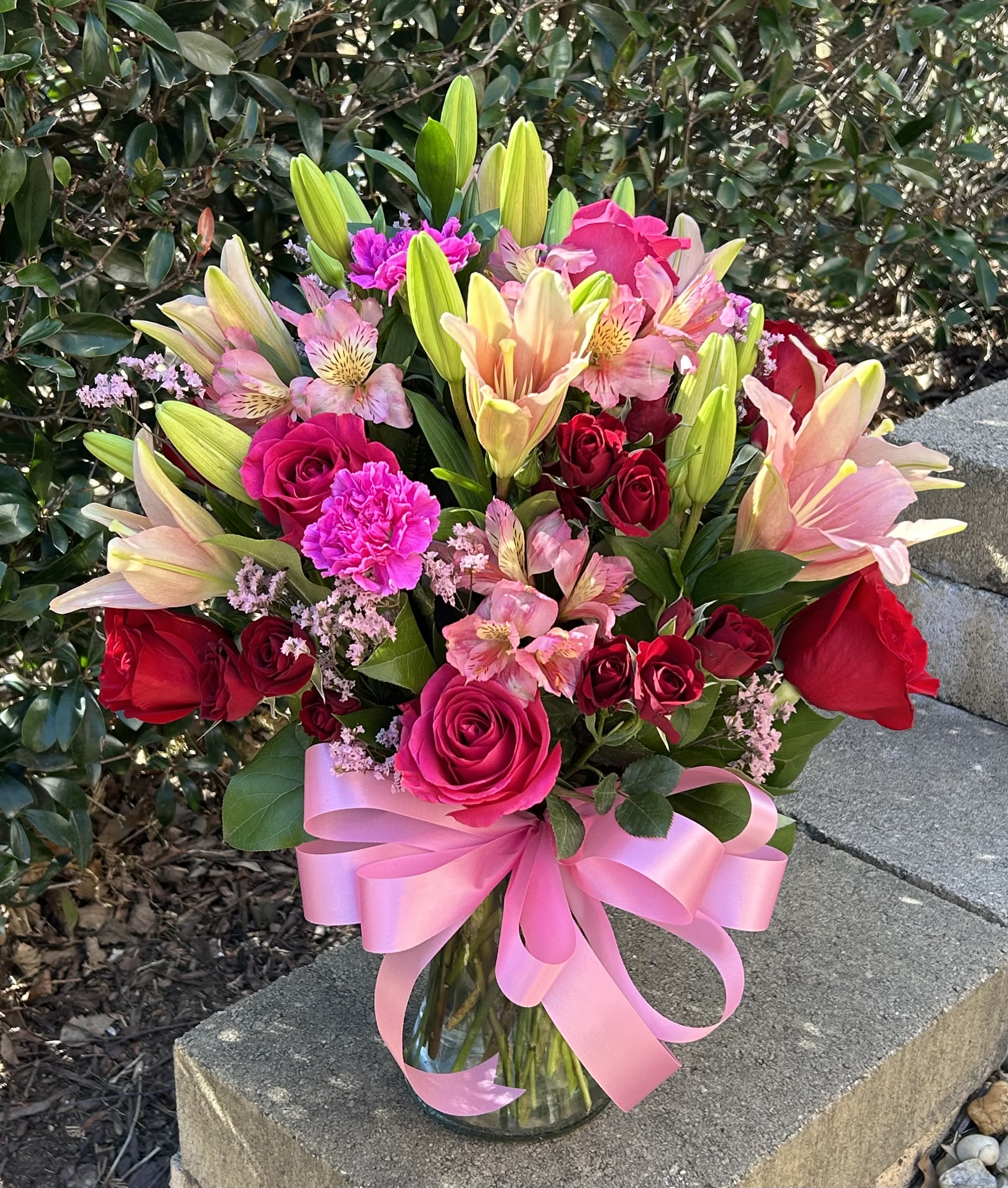 Lilies &amp; Roses - A pink and red bouquet of roses, lilies, carnations, spray roses, and alstroemerias arranged in a round and traditional style.