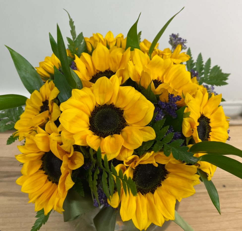 Sunshine express - Cylinder Vase with a bed of sunflowers. The uplifting hue is naturally associated with sunshine, and lends the flower its innate cheerful vibe. Yellow alone is representative of happiness, joy, virility, intelligence, and friendship. All of these characteristics make the yellow sunflower a particularly thoughtful option to give to a dear friend or a significant other.