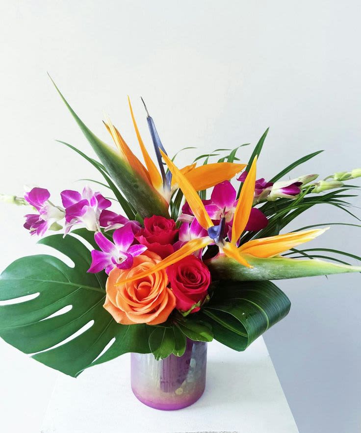 Paradise - This stunning composition is a visual feast for the senses. It features a dazzling array of tropical flowers and foliage set against the backdrop of a mesmerizing, shimmering container.