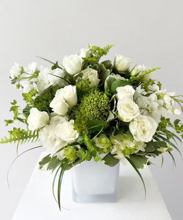 White Garden - This white and green flower arrangement in a white cube vase is a stunning display of elegance and simplicity. Its harmonious color palette and tasteful design create a captivating centerpiece or decorative accent, evoking a sense of tranquility and beauty.