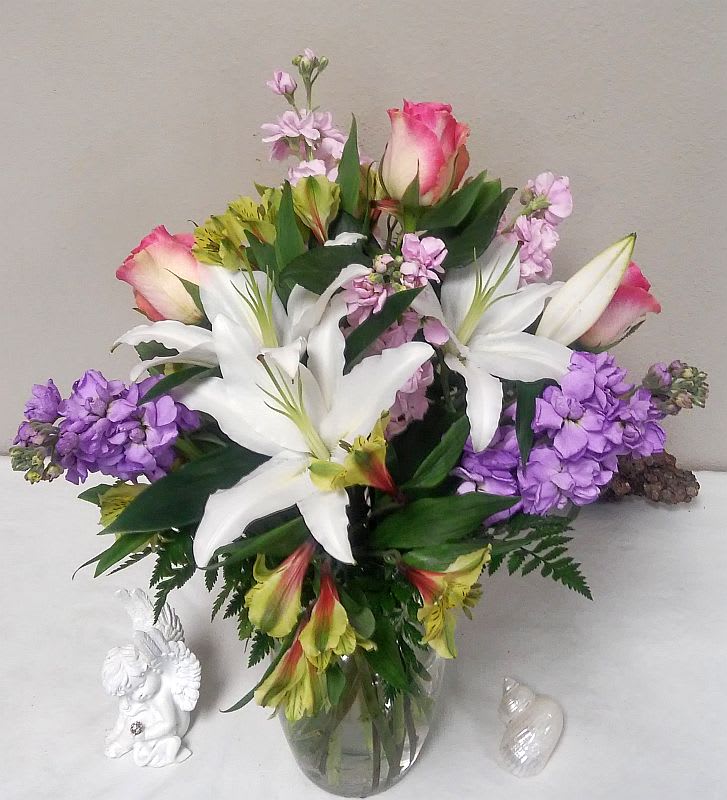 Flirty Floral - Sometimes the simple things in life can bring the most joy – and this flirty mix of pink and peach blossoms, mixed with greenery and presented in a clear glass sweetheart vase – is bright, pretty and perfect for any occasion.