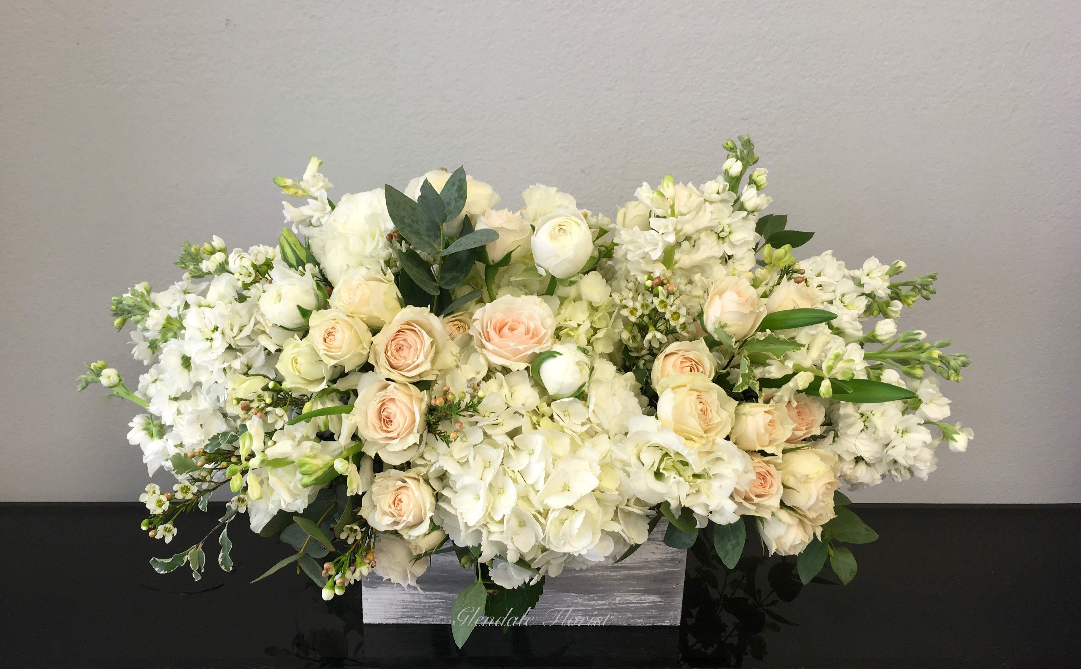White Dream - Glendale Florist - All white hydrangeas, roses, stock, and seasonals carefully arranged in a birchwood box. It stands approximately 14-16'' tall and approximately 26'' wide. 