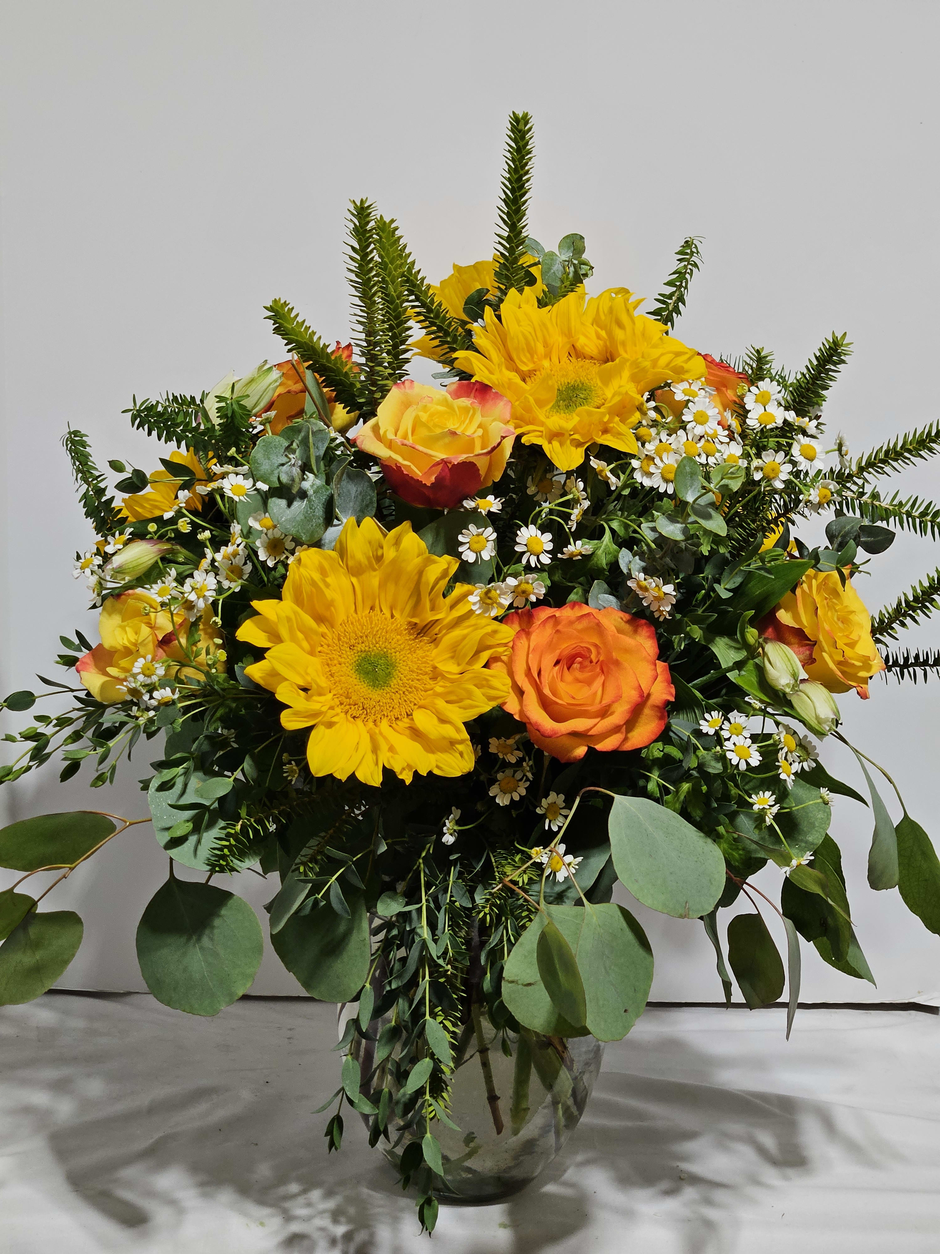 Sending Sunshine - Brighten someone's day with this beautiful bouquet designed by our expert designer's. Created using the freshest Yellow Roses, Sunflowers, Alstromeria, Bells of Ireland( Deluxe and Premium),  Chamomile or baby's breath and lush greenery in a clear glass vase.