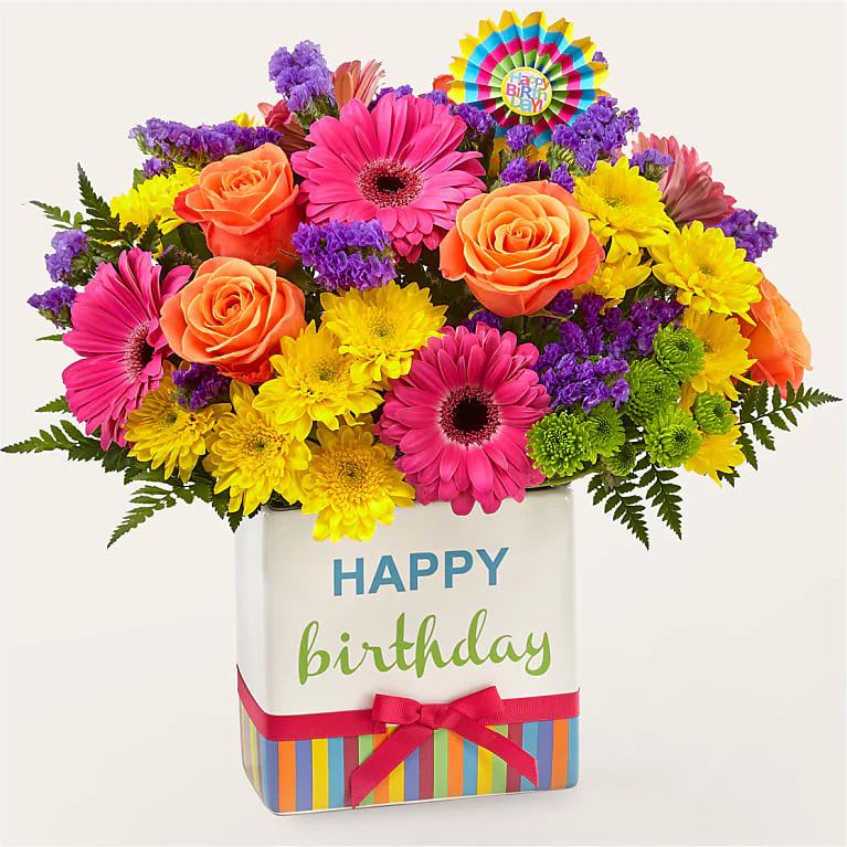 Birthday Brights Birthday Brights - Birthday Brights Floral Arrangement Radiant Roses – A stunning focal point with a vibrant orange and yellow rose, symbolizing joy and admiration. Charming Carnations – Beautiful red and purple carnations add texture and a touch of elegance. Delightful Daisies – Cheerful yellow daisies bring a sunny and uplifting vibe. Lovely Alstroemeria – Soft and delicate, representing friendship and devotion. Monte Casino & Fillers – Accents of purple monte casino and lush greenery enhance the fullness and beauty of the bouquet. Presented in a festive "Happy Birthday container with a Happy Birthday Pic , this arrangement is perfect for birthdays, celebrations, and special moments!