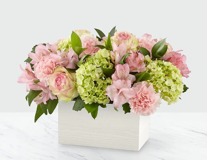 Moments with Mom (square) - Celebrate the simple, unforgettable moments shared with her.  Introducing Moments with Mom  — a soft, elegant floral design that captures the calm, nurturing essence of motherhood through delicate textures and tender hues.  This arrangement brings together pastel pink roses, green hydrangeas, blush alstroemerias, and ruffled carnations, nestled in a modern white wooden box. The result is a refined and airy composition that radiates affection, balance, and peace.  Moments with Mom is a gentle and timeless tribute — perfect for celebrating quiet strength, deep connection, and the beauty of everyday love.    Dimensions: Height: 30 cm (12 inches) Width: 35 cm (14 inches)    Pre-book online! Now available  in Miami’s districts.  #MomentsWithMom #LuxuryFlowers #MothersDayGift #SoftBlooms #PastelFlorals #MiamiFlorist #ElegantFlowers 