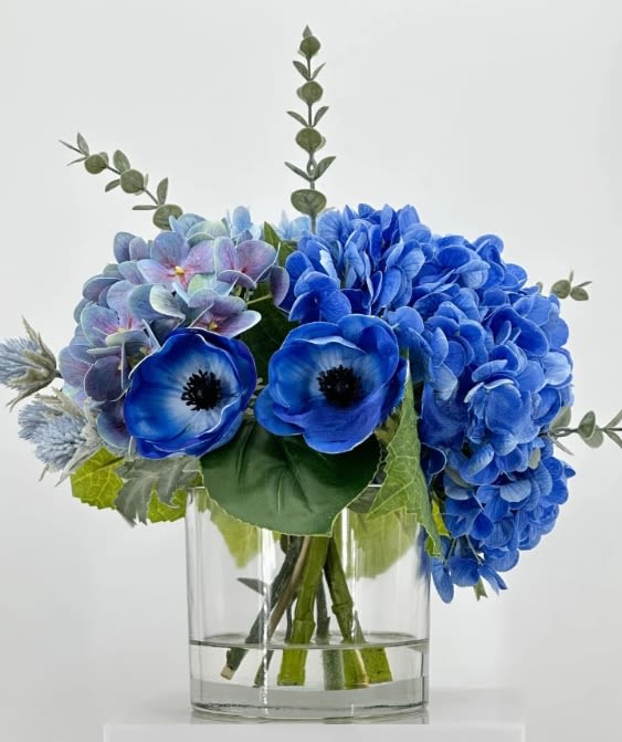 For Ever My Mom - For the woman who has been your forever — your strength, your calm, your everything. Introducing For Ever My Mom  — a striking floral arrangement that symbolizes loyalty, serenity, and eternal love.  Designed in captivating shades of blue and violet, this bouquet blends lush hydrangeas, delicate anemones, and soft accent florals in a clear modern glass vase. The composition feels bold yet tranquil — an elegant tribute to the irreplaceable presence of a mother who will always be your forever.  Sophisticated, memorable, and full of depth, For Ever My Mom is a luxurious floral statement for heartfelt gratitude and everlasting admiration.    Dimensions: Height: 35 cm (14 inches) Width: 30 cm (12 inches)    Available for pre-order with limited availability. Delivery available in Miami’s districts.   Please note: Due to the natural variation of blue pigments in fresh flowers, the final shade of blue in the arrangement may vary slightly from the photo. We always ensure the integrity and harmony of the overall design.  #ForEverMyMom #LuxuryFlorals #BlueHydrangeas #MothersDayGift #MiamiFlorist #TimelessLove #ElegantFlowers 