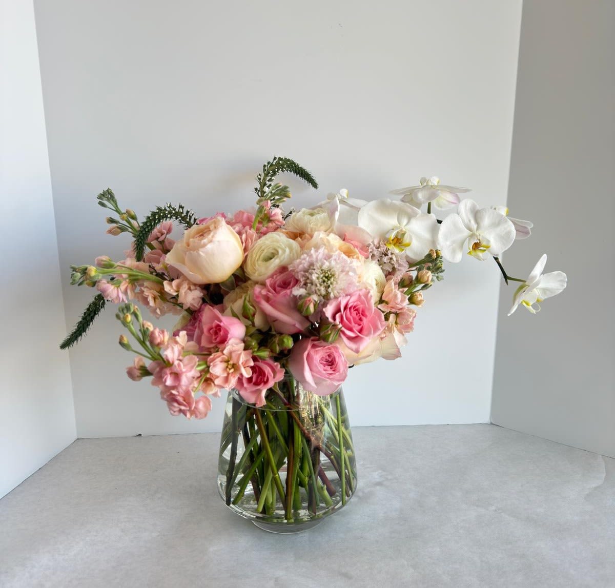 Caring Mom Caring Mom - Soft, nurturing, and endlessly graceful — just like her love. Introducing Caring Mom — a romantic and refined floral arrangement that captures the gentle presence and heartfelt warmth of a caring mother. This design features a lush mix of blush garden roses, soft peach ranunculus, stock, delicate scabiosa, and graceful white phalaenopsis orchids. Arranged in a modern teardrop glass vase, the bouquet flows with movement, emotion, and effortless elegance. Caring Mom is a sophisticated floral gesture for the woman whose kindness and care shape every moment with quiet beauty. Dimensions: Height: 40 cm (16 inches) Width: 35 cm (14 inches) Now available for pre-order with same-day delivery in Miami’s most exclusive areas. #CaringMom #LuxuryFlorals #MothersDayGift #SoftBlooms #ElegantBouquet #MiamiFlorist #OrchidsAndRoses