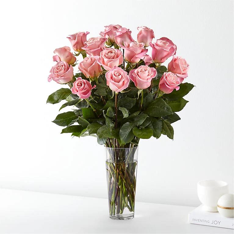 Two Dozen Long Stem Pink Roses - Dive into a tender romance with Irvine Village Flowers’ charming creation—two dozen premium pink roses, a bouquet that blooms with the softest whispers of love. Nestled in a clear vase, these delicate beauties shine in shades of pink, their velvety petals unfurling like a blush across a lover’s cheek. Each rose is a hand-picked treasure, crafting a sweet scene that’s both timeless and heartfelt, a perfect gift to wrap someone special in affection.  Every bloom tells a story of the heart: these premium pink roses, lush and radiant, sing of admiration and gratitude, their gentle hue a melody of tender feelings. They sway together in the clear vase, a crystal stage that lets their beauty dance in the light, a symbol of love’s quiet joy. From Irvine Village Flowers, this arrangement is a romantic keepsake. Stop by our shop or order online, and let our seamless delivery bring this sweet delight to your doorstep, fresh and ready to sprinkle your world with the magic of pink roses.
