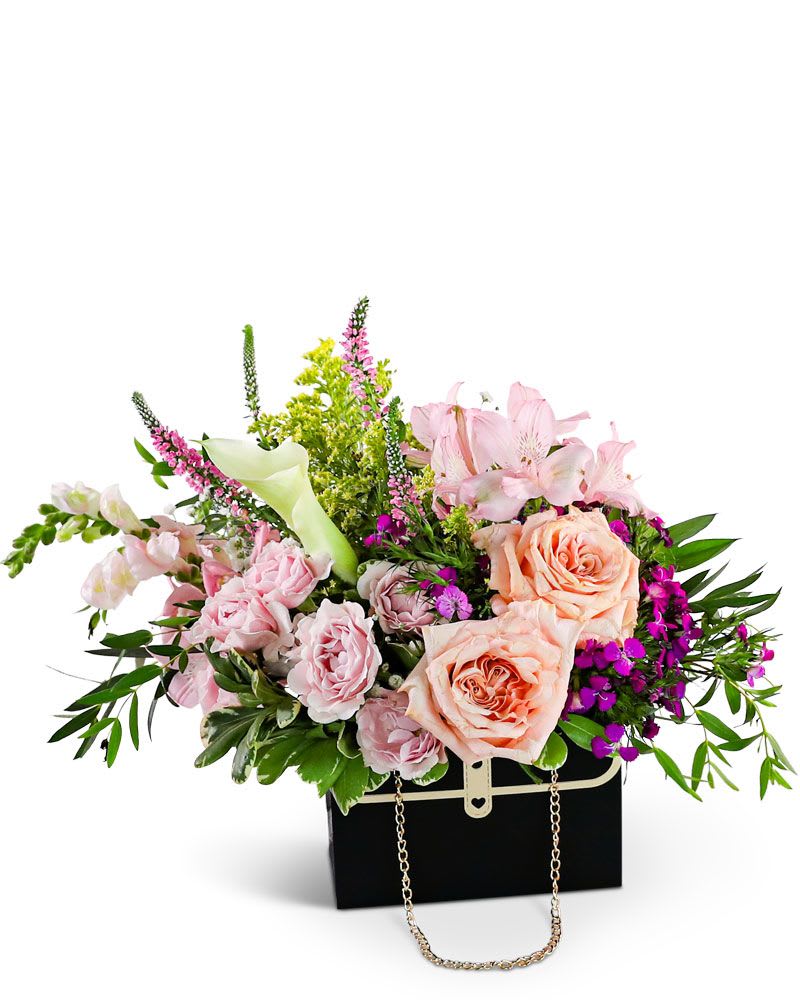 Botanical Belle Handbag - &quot;The Botanical Belle Handbag is a stunning floral design that captures the beauty of wildflowers in a chic way. Featuring mini Calla lilies, Roses, Alstroemeria, Snapdragons, and lush foliage, this handbag arrangement creates a mesmerizing and natural appeal. With its timeless color palette and fashionable flower box purse, it's not just a floral display but a versatile keepsake container that adds elegance to any setting. As a trusted local florist, we take pride in every order, offering hand-crafted flower designs delivered directly to the recipient. Our flower shop is committed to providing the highest quality, freshest flowers, and ensuring timely delivery for every arrangement.&quot;