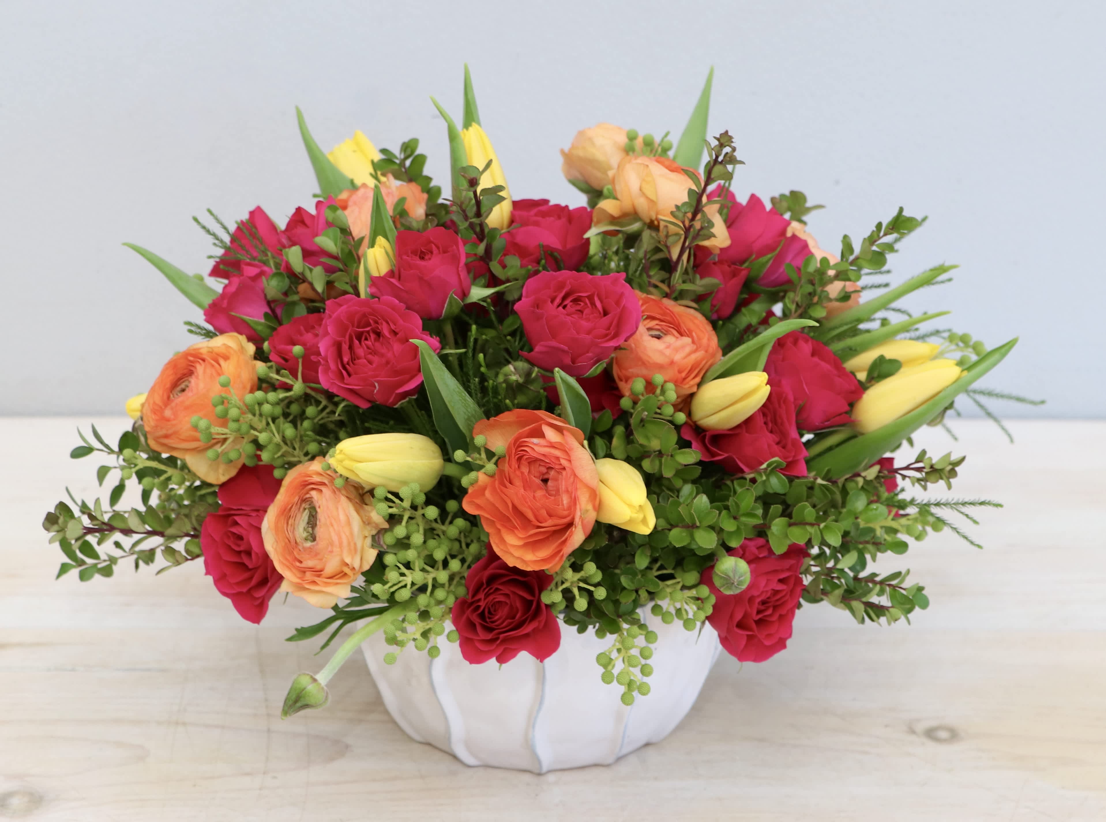 Summer Fiesta - WeHo Summer Fiesta - WeHo - This joyful arrangement is made with bright pink spray roses, orange ranunculus, and yellow tulips.