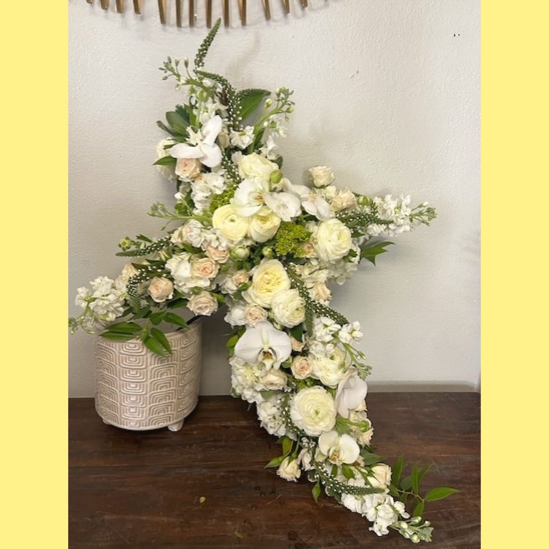Garden Cross in Neutral Colors Garden Cross in Neutral Colors - A Versatile Tribute for Celebrations and Remembrances The "Garden Cross in Neutral Colors" is a stunning floral arrangement that beautifully complements any occasion, from Easter celebrations to christenings, or as a tribute to honor someone whose faith was central to their life. This exquisite cross features a harmonious blend of white, cream, blush, and green florals, including hydrangeas, garden roses, miniature roses, orchids, and ranunculus when available. Elegant Florals: The selection of neutral-toned flowers creates a serene and sophisticated display, perfect for both joyous celebrations and solemn remembrances. Natural Accents: Complemented by lush greenery, this arrangement offers a natural and elegant touch that enhances its beauty. Seasonal Variations: While the core design remains consistent, seasonal variations in flower and greenery selection ensure a fresh and vibrant display. Choose the "Garden Cross in Neutral Colors" from Elizabeth's Garden to adorn your home or event with a meaningful and versatile floral tribute, celebrating faith and life's special moments with grace and elegance.