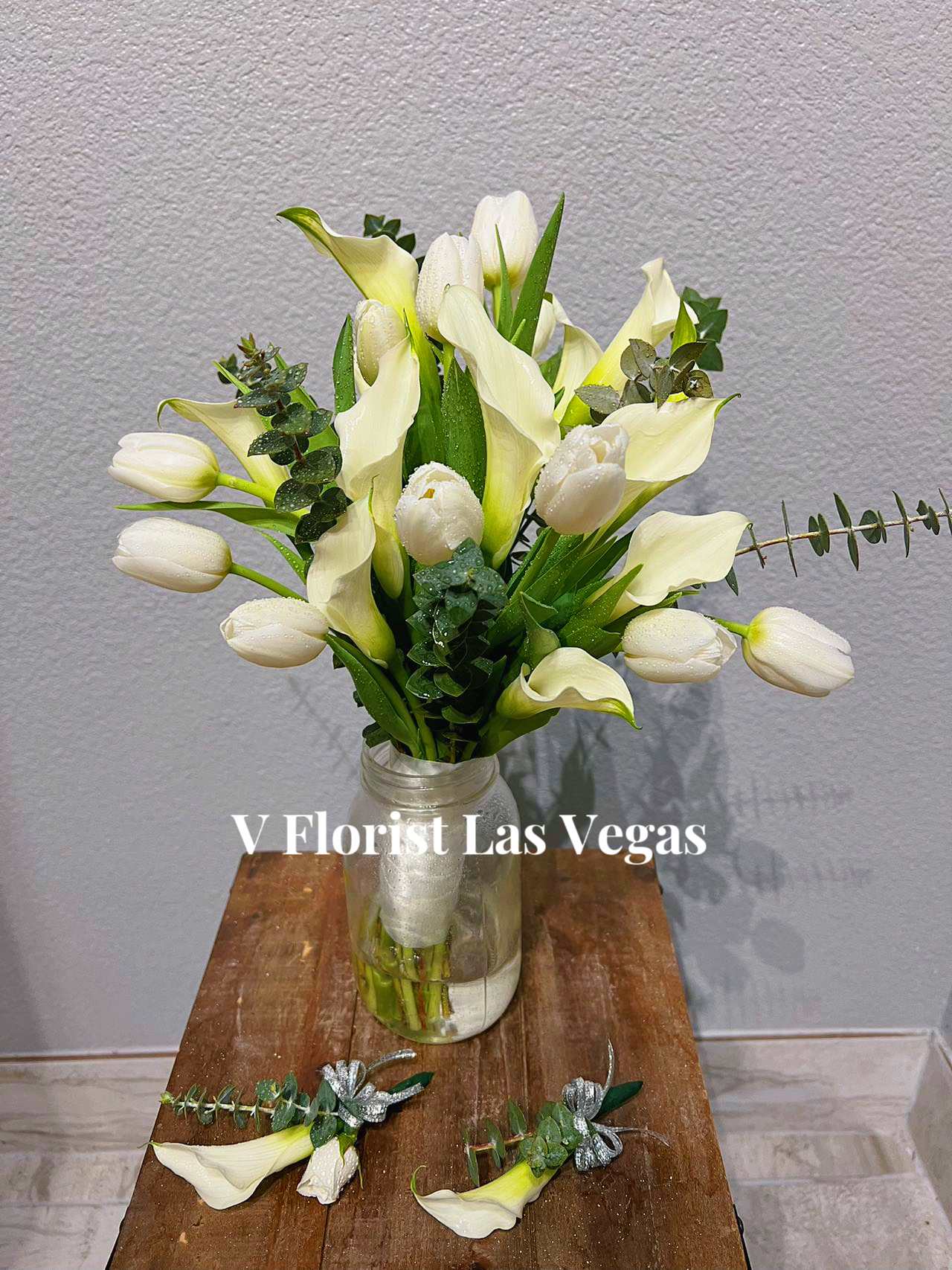 Calla lily and Tulip bridal bouquet with groom boutonniere and groomsman boutonniere - On your wedding day, nothing is more classic or elegant than an all-white bouquet. We’ve filled ours with white calla lilies and White tulip, finished it off with a matching white satin ribbon. Beautifully hand-arranged by our team of expert florists, it’s as perfect a pairing as the happy couple. Stunning hand-designed bouquet of white roses, white calla lilies and white spray roses accented with a crisp white satin ribbon All of our wedding flowers are hand-designed and arranged at a local florist to ensure they arrive looking their best on the big day Our florists select the freshest flowers available so floral colors and varieties may vary Orders must be placed two weeks in advance to allow for processing