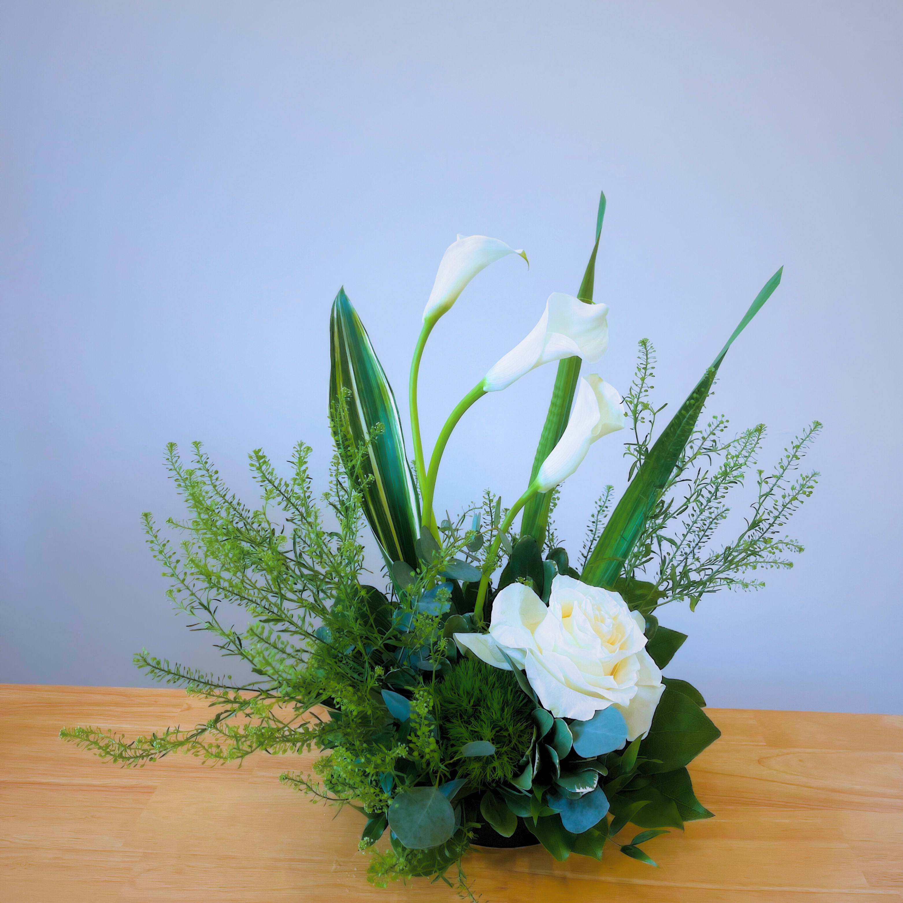 Zen Garden Elegance Zen Garden Elegance - A serene and sophisticated arrangement featuring pure white calla lilies and a single white rose, symbolizing peace and harmony. Inspired by the tranquility of a Zen garden, this minimalist design exudes elegance and balance. Perfect for creating a calming atmosphere in any space or as a thoughtful gift.