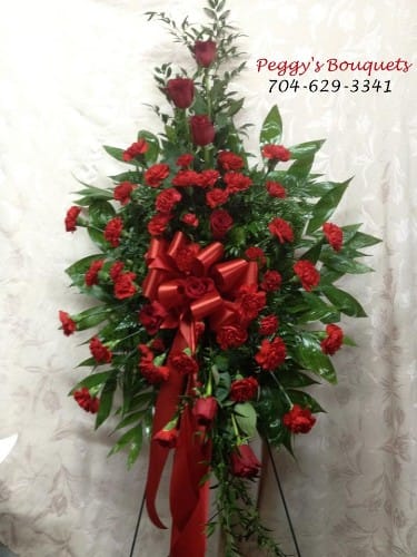 A Seat At The Master's Table A Seat At The Master's Table - All red standing spray. Red roses, red carnations and red mini carnations make this the perfect tribute for any loved one.