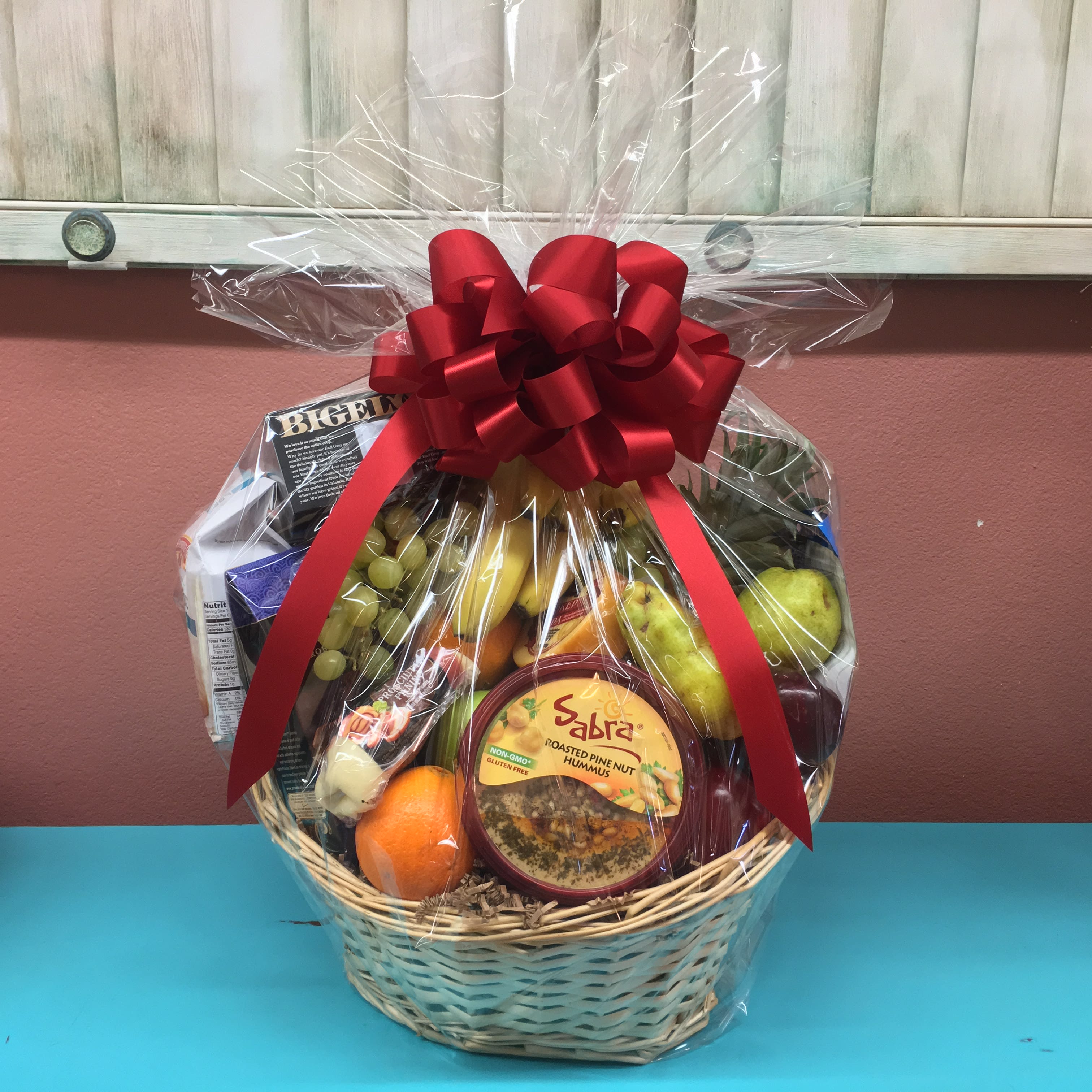 Premium Gourmet Gift Basket - Life really is a picnic for the receiver of this delicious gourmet basket. Overflowing with Red and green apples, bananas, pears, oranges, a pineapple, green grapes, hummus, cheeses and crackers, gourmet chocolates and cookies and  tea. This feast comes delivered in a wicker basket complete with red organza ribbon. Baskets May Vary.    Please note:  This item may require additional lead time so same-day delivery may not be available. 