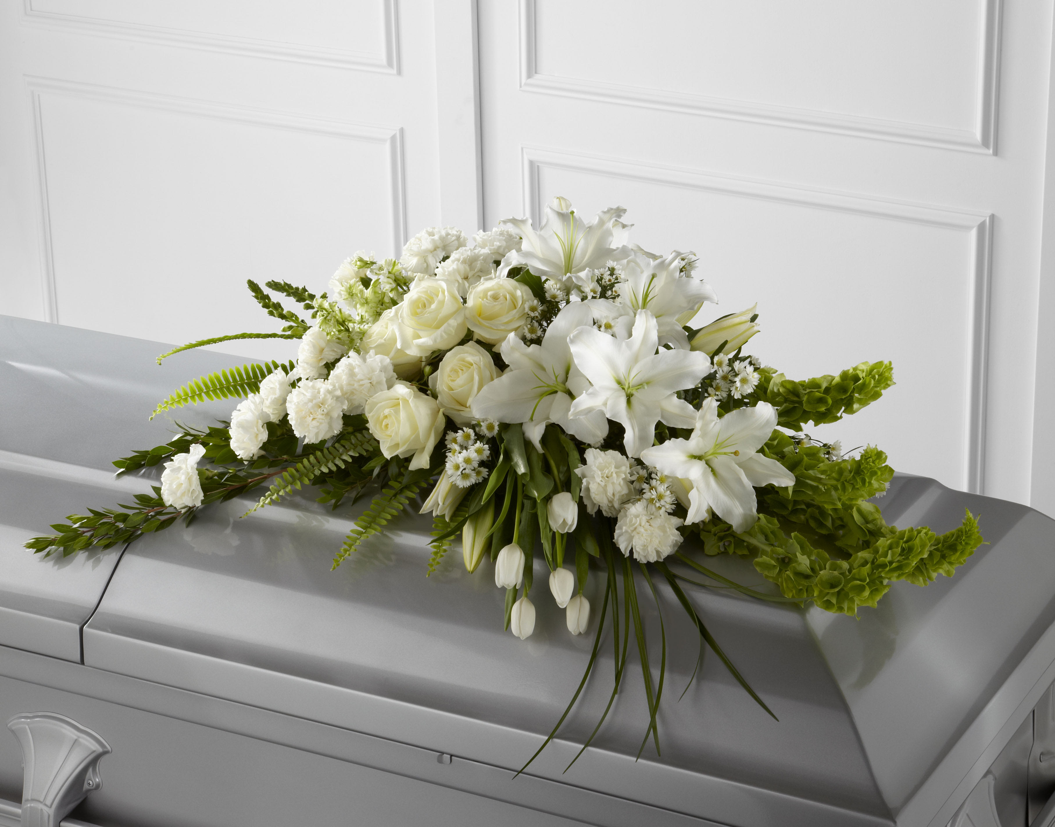 Resurrection Casket Spray Resurrection Casket Spray - The Resurrection Casket Spray inspires thoughts of comfort and peace to those wishing to pay their respects for the loss of the deceased. White tulips, roses, snapdragons, Oriental lilies, larkspur, carnations and monte casino asters are accented by the bright green stems of Bells of Ireland and an assortment of the finest lush greens to create the perfect arrangement to display on the top of their casket during their final farewell service.