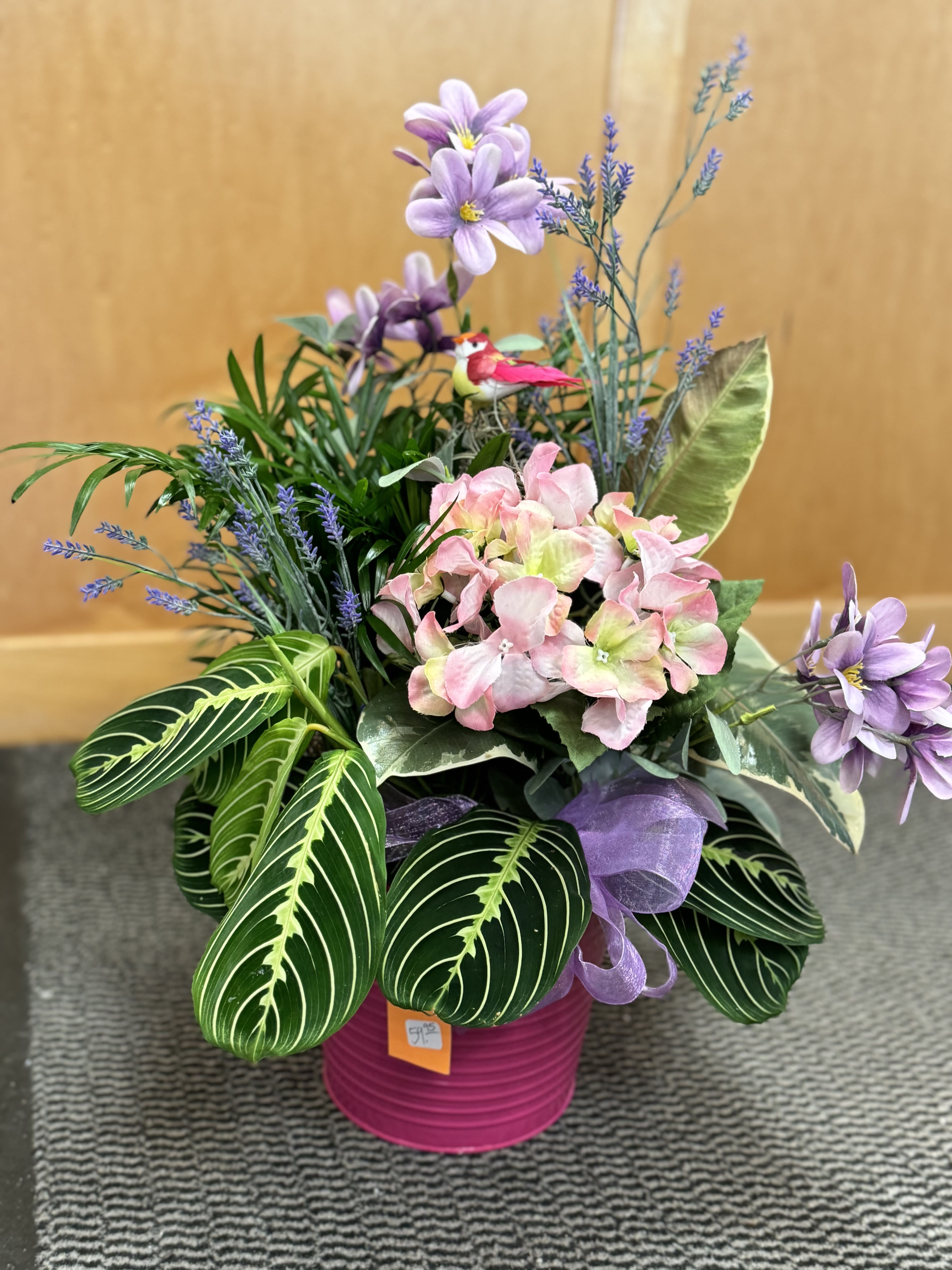 Bird Dish garden - This combination planter features 3 different green plants potted in a pink bucket, accented with pink and purple silk flowers and a pretty pink bird right in the center.