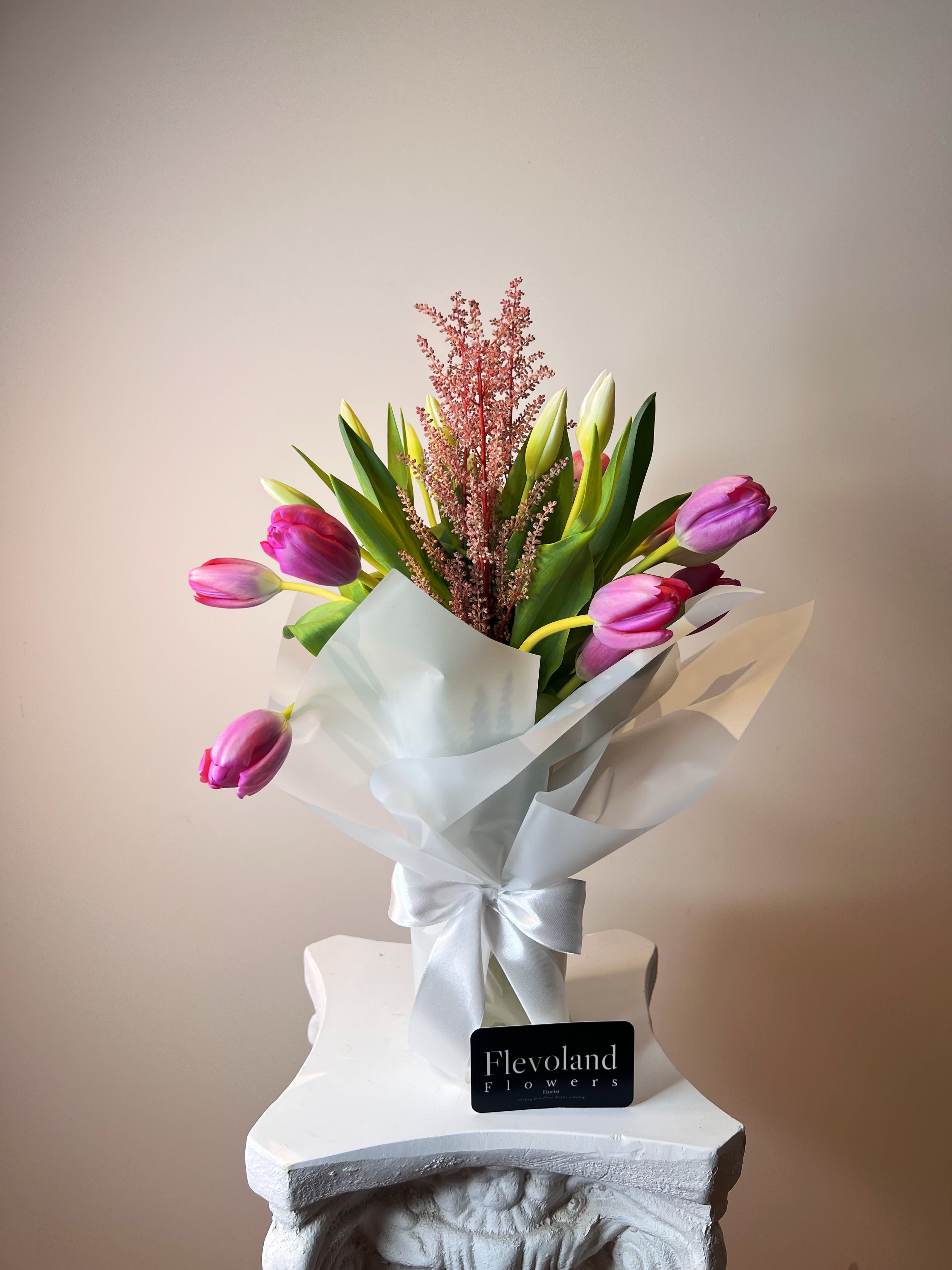 Tulips in a Vase - Twenty tulips arranged with care in a glass vase, softly wrapped in white paper. A blend of elegance and simplicity—fresh, minimal, and full of feeling. The kind of gesture that speaks for itself.  Timeless. Thoughtful. Always in season.