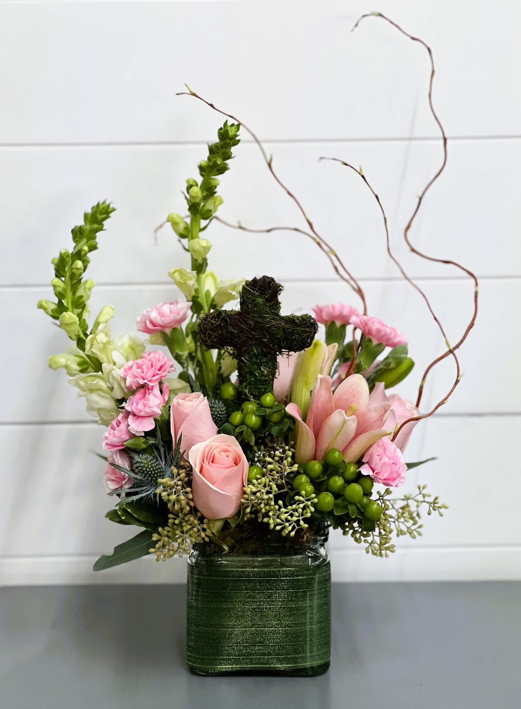 Life's Blessings Life's Blessings - Celebrate Easter with an arrangement that includes beautiful pink roses, pink carnations and spring greenery in a 4" cube vase accented with a small moss covered cross.