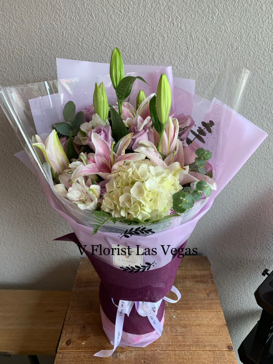 Deluxe Lavender And White Bouquet-Style 2 Deluxe Lavender And White Bouquet-Style 2 - Deluxe Asian style wrapped bouquet with lavender roses, white hydrangeas, stargazer lilies, and fillers. Our florists select the freshest flowers available, so colors and varieties may vary due to local availability.