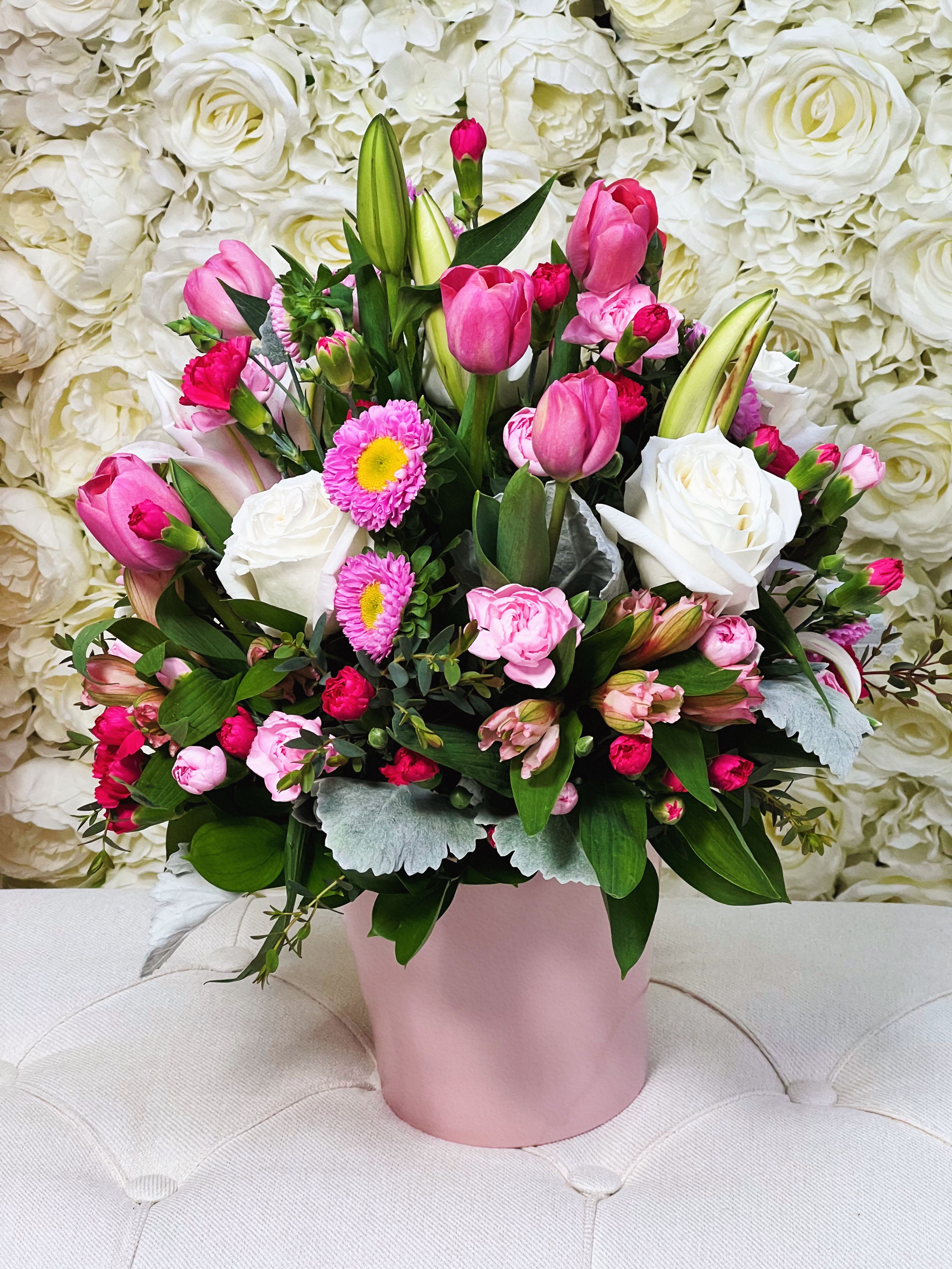 Pink Dream - A delicate floral arrangement in soft pink and white tones that evokes tenderness, sweetness, and elegance. Featuring pink tulips, white roses, alstroemerias, asters, mini carnations in pink and fuchsia, and stunning stargazer lilies. Perfect to express love, gratitude, or simply brighten someone’s day.  19”H x 14”W